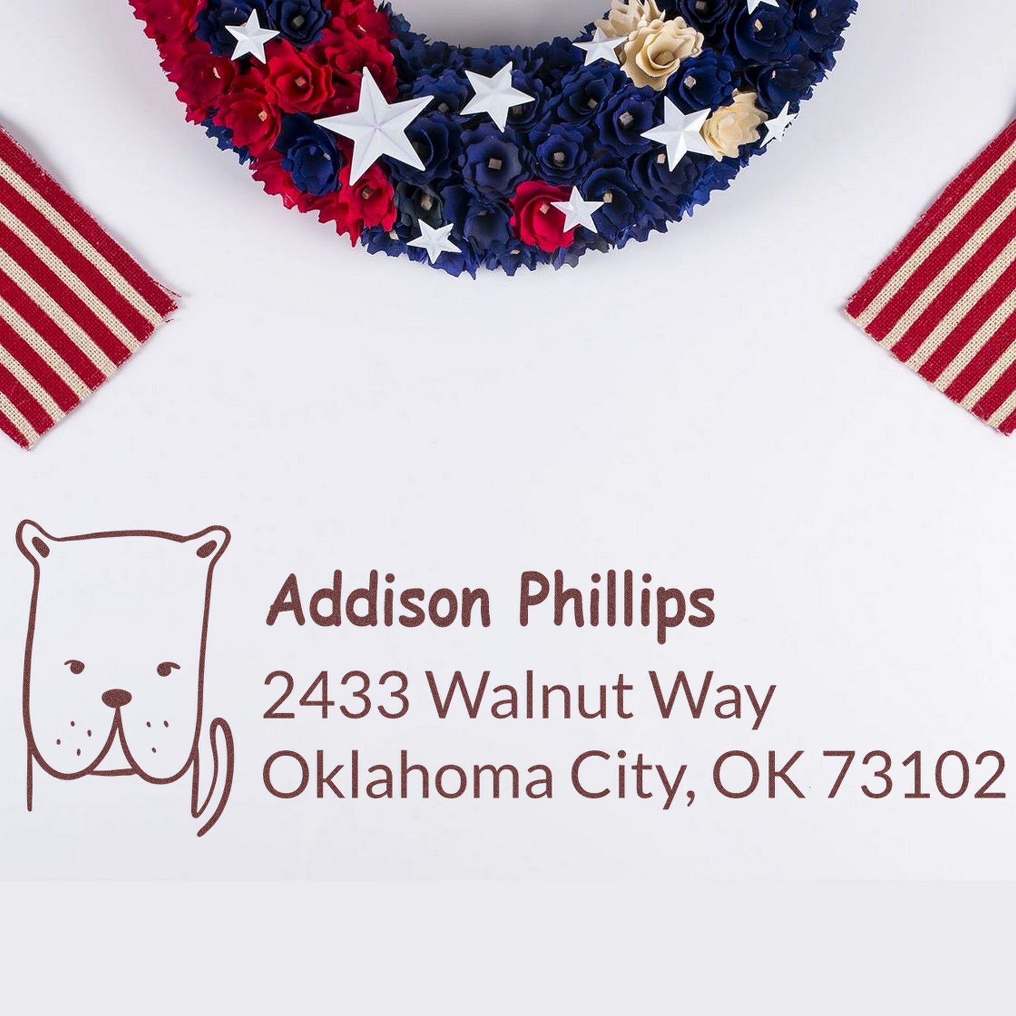 Image of a Wood Handle Daring Dog Customized Address Label Rubber Stamp impression on paper. The Custom New Address Stamp features a cute dog illustration with the name Addison Phillips and address 2433 Walnut Way, Oklahoma City, OK 73102, surrounded by patriotic decor.