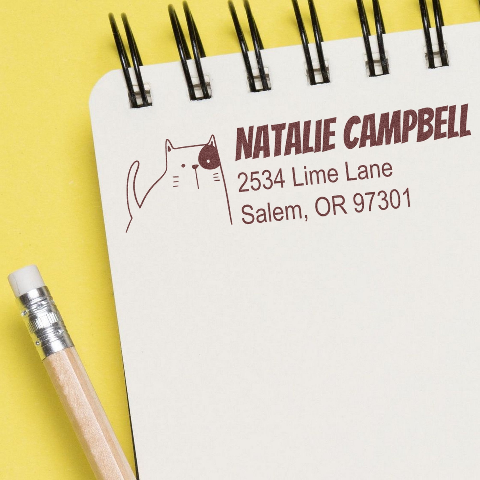 PSI Charming Cat Customizable Address Return Pre-Inked Stamp on a notepad, featuring a cute cat illustration and personalized address. Ideal for a Customized Return Mail Stamp, shown with a pencil on a yellow background.