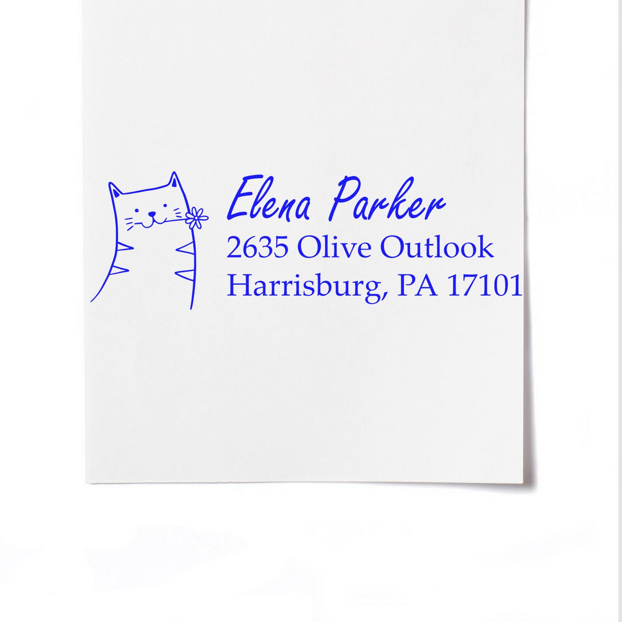 PSI Fluffy Feline Customizable Mailing Address Pre-Inked Stamp featuring a cute cat design and personalized text. The Customized New Address Stamper displays "Elena Parker, 2635 Olive Outlook, Harrisburg, PA 17101" in blue ink on white paper.