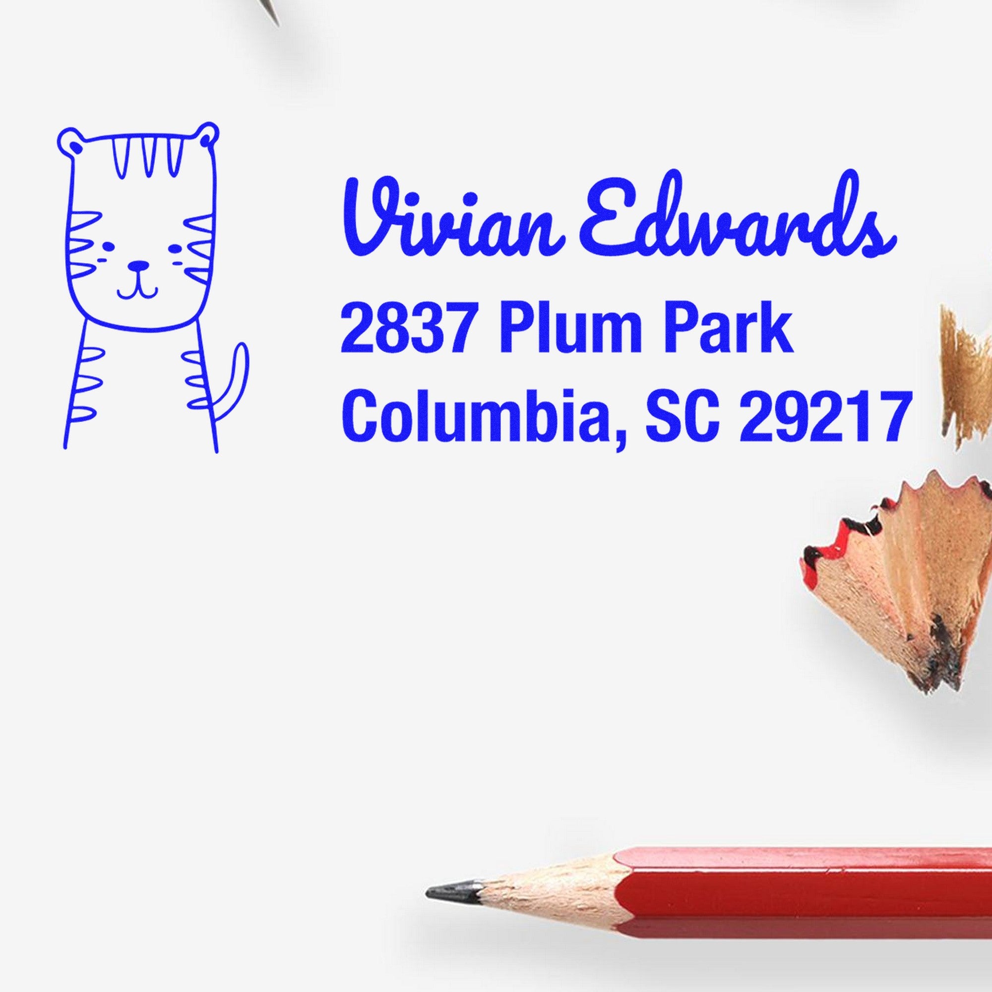 Terrific Tiger Custom Address Return Self-Inking Stamp featuring a cute tiger illustration and the text "Vivian Edwards, 2837 Plum Park, Columbia, SC 29217." Ideal for a Custom New Address Stamp. Pencils and shavings are visible around the stamp.
