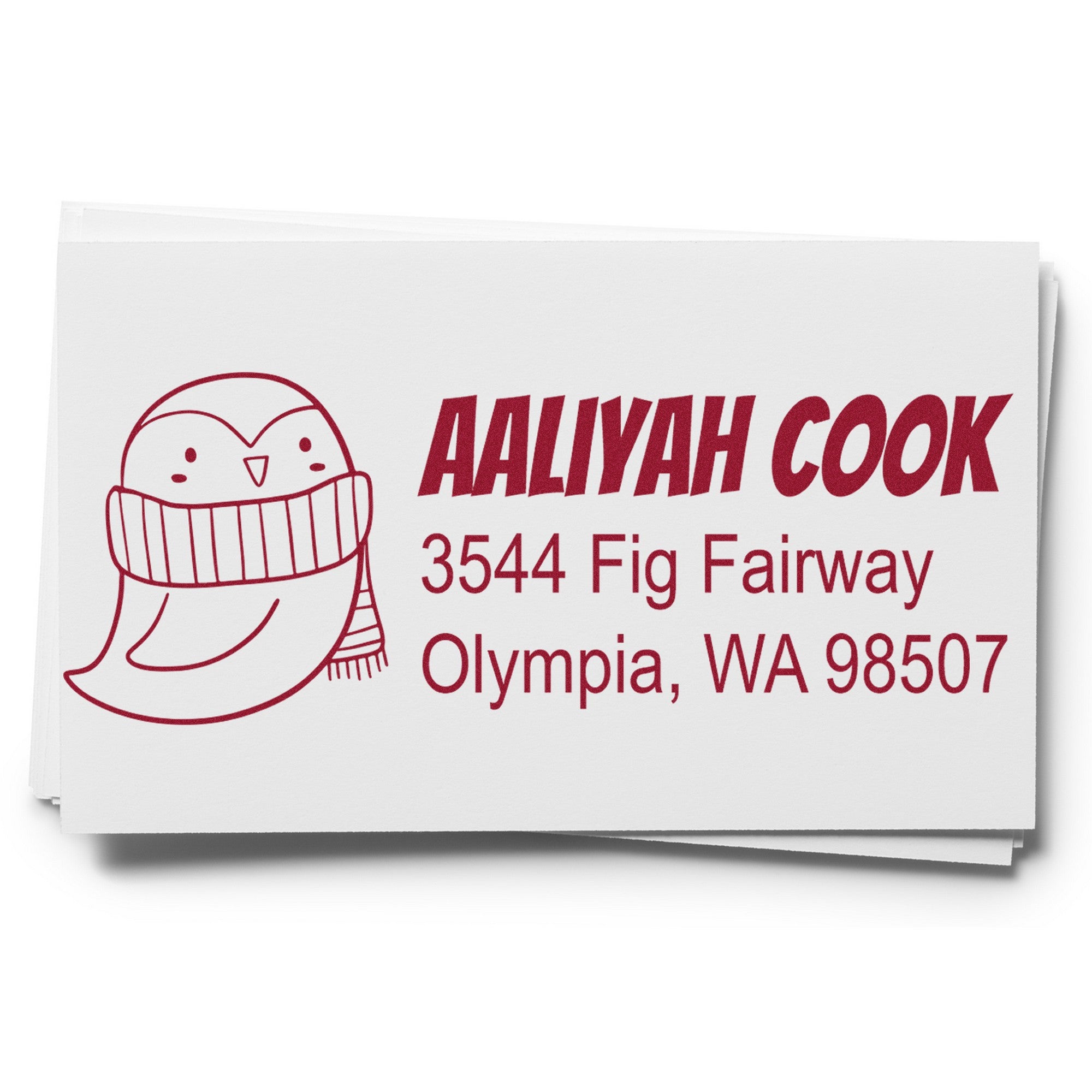 Image of a custom mailing stamper featuring a pretty penguin design with a wood handle. The rubber stamp is used for home addresses on envelopes, displaying "Aaliyah Cook, 3544 Fig Fairway, Olympia, WA 98507" in red text.