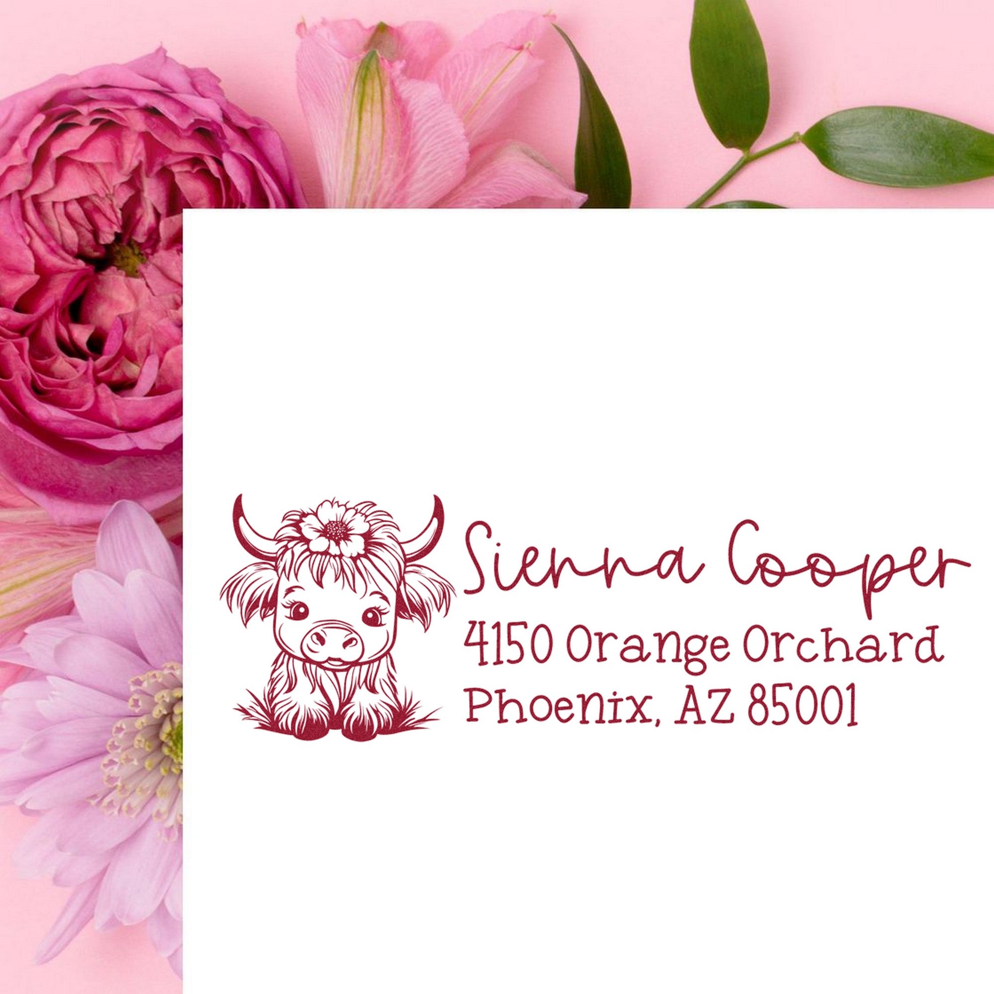 Maroon custom return address stamp with cow illustration on white card, framed by pink flowers and green leaves.