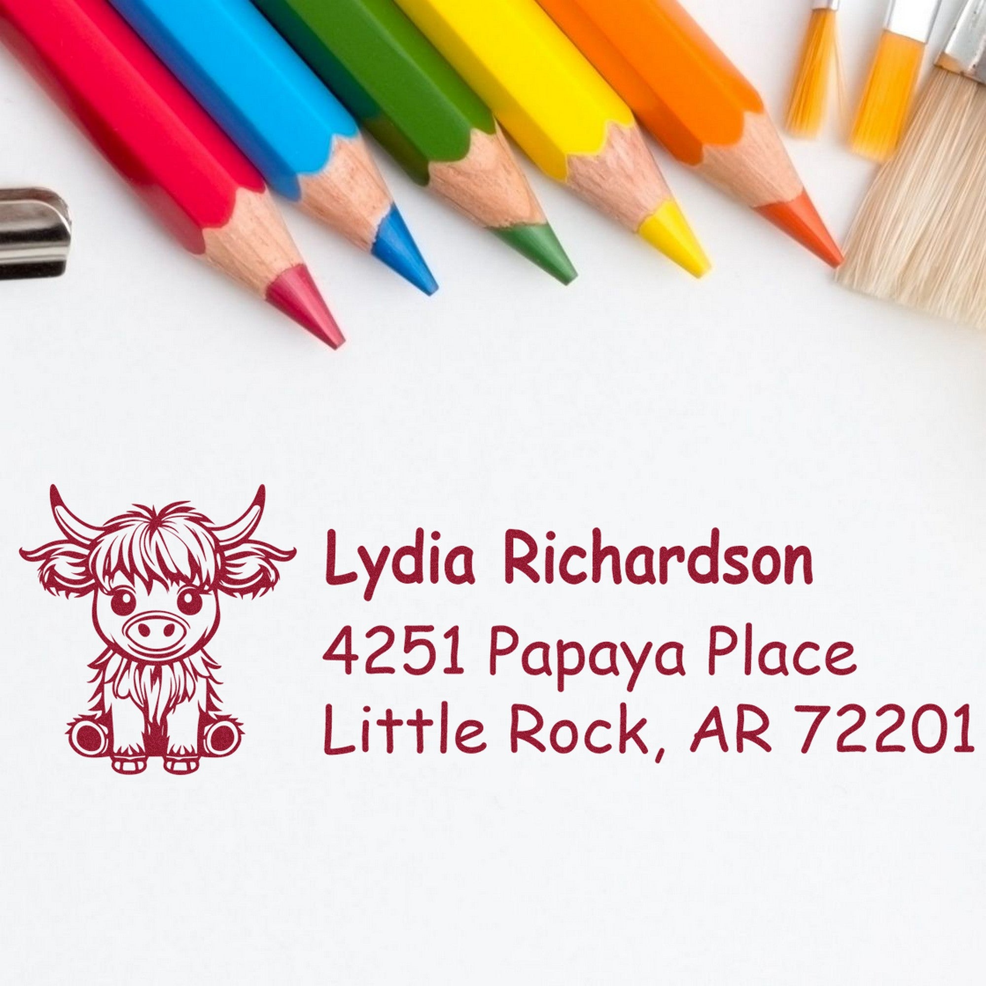 Multicolor pencils above a maroon custom address stamp and seal with cow icon, Lydia Richardson, Little Rock, AR 72201.