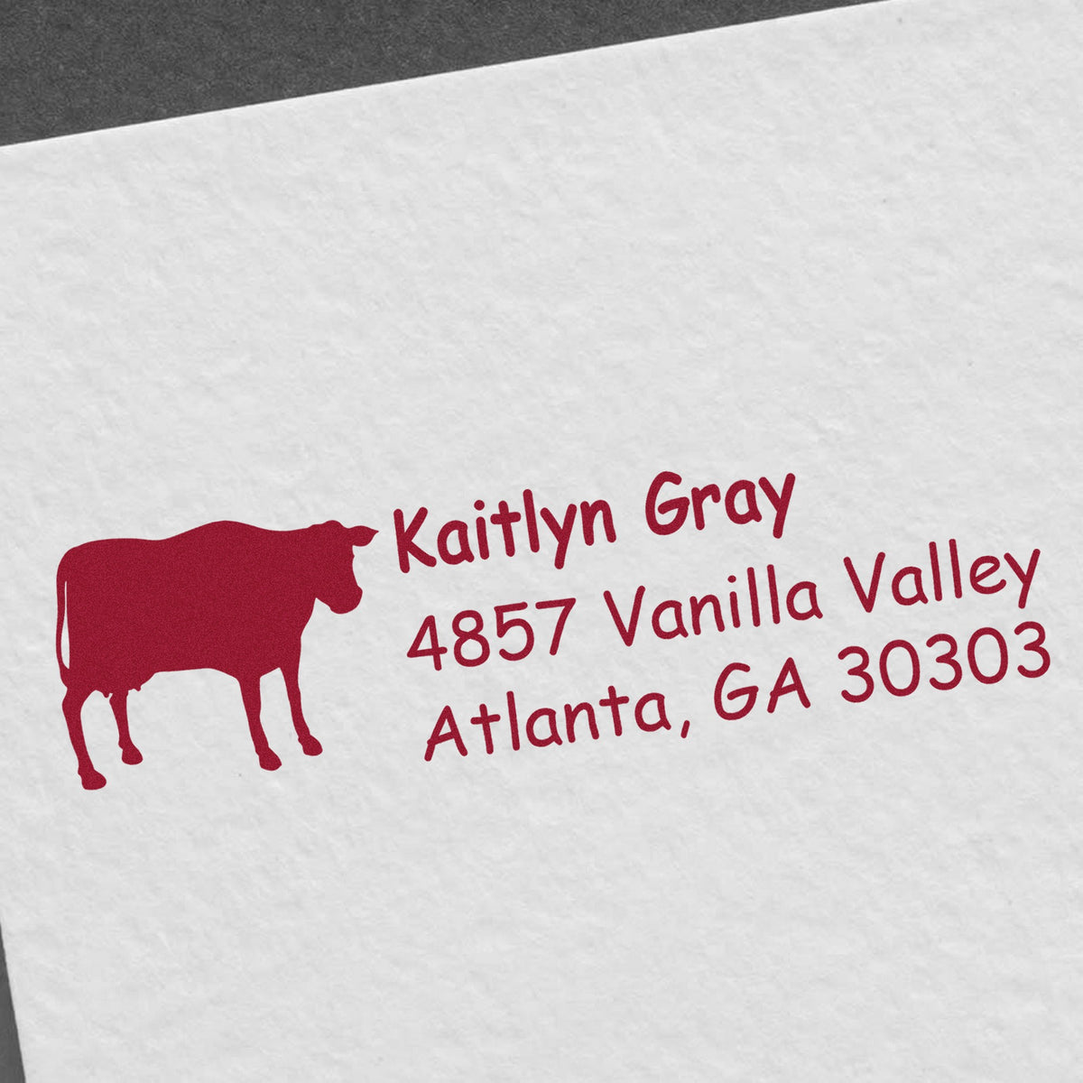 Red custom return address stamp with cow silhouette and Kaitlyn Gray, Atlanta, GA 30303 on white paper