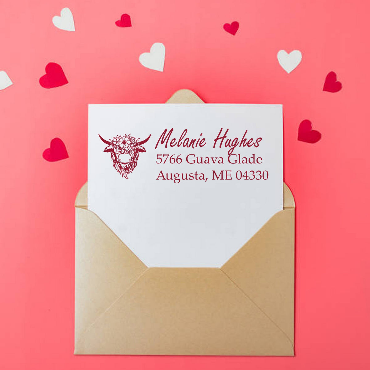 Custom burgundy address stamp and seal on white envelope, with heart confetti on a pink background.