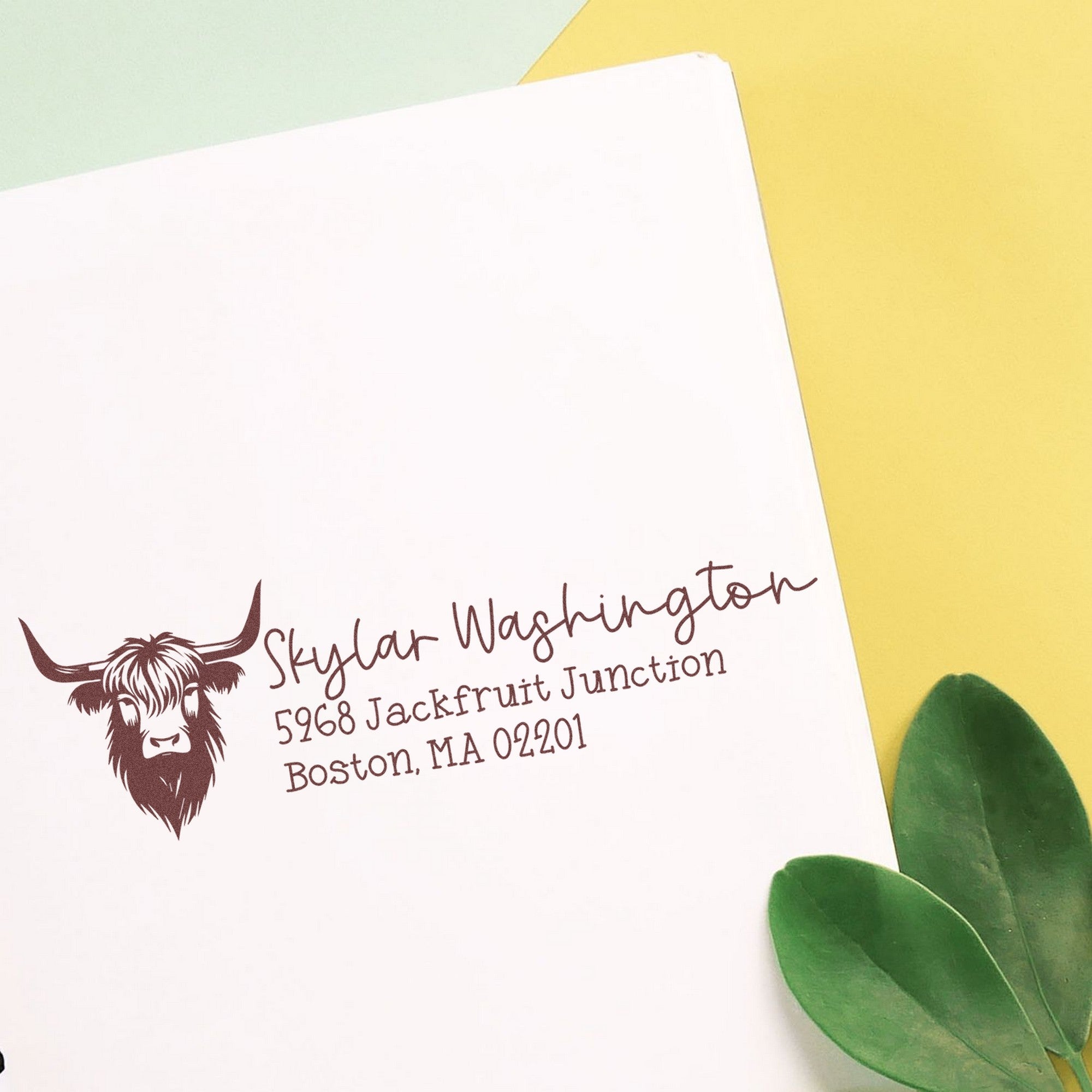 Brown custom return address stamp seal for Skylar Washington, with highland cow logo on white paper and soft yellow-green background.