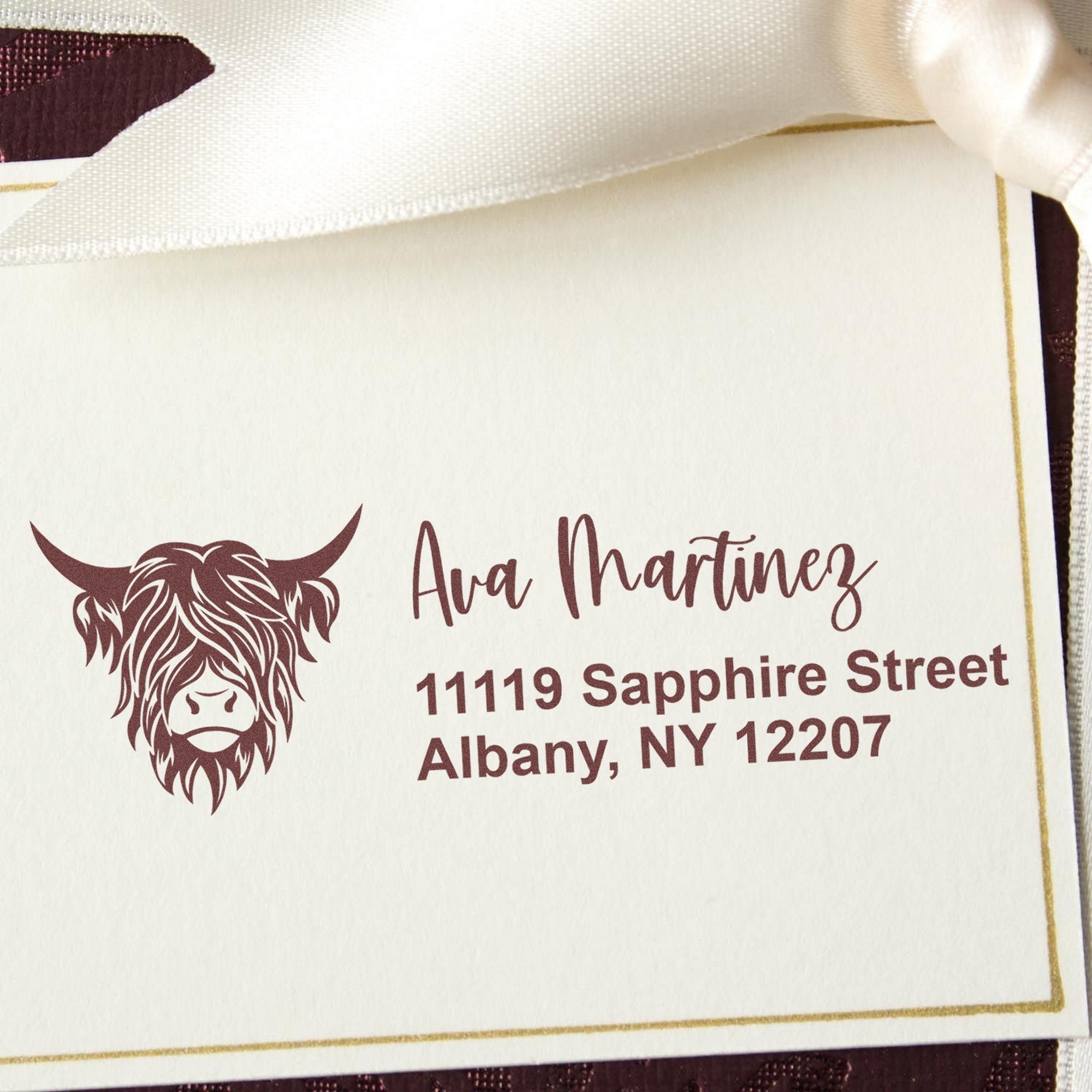 Maroon custom stamp and seal with Highland cow logo, Ava Martinez name, and gold-bordered white card.