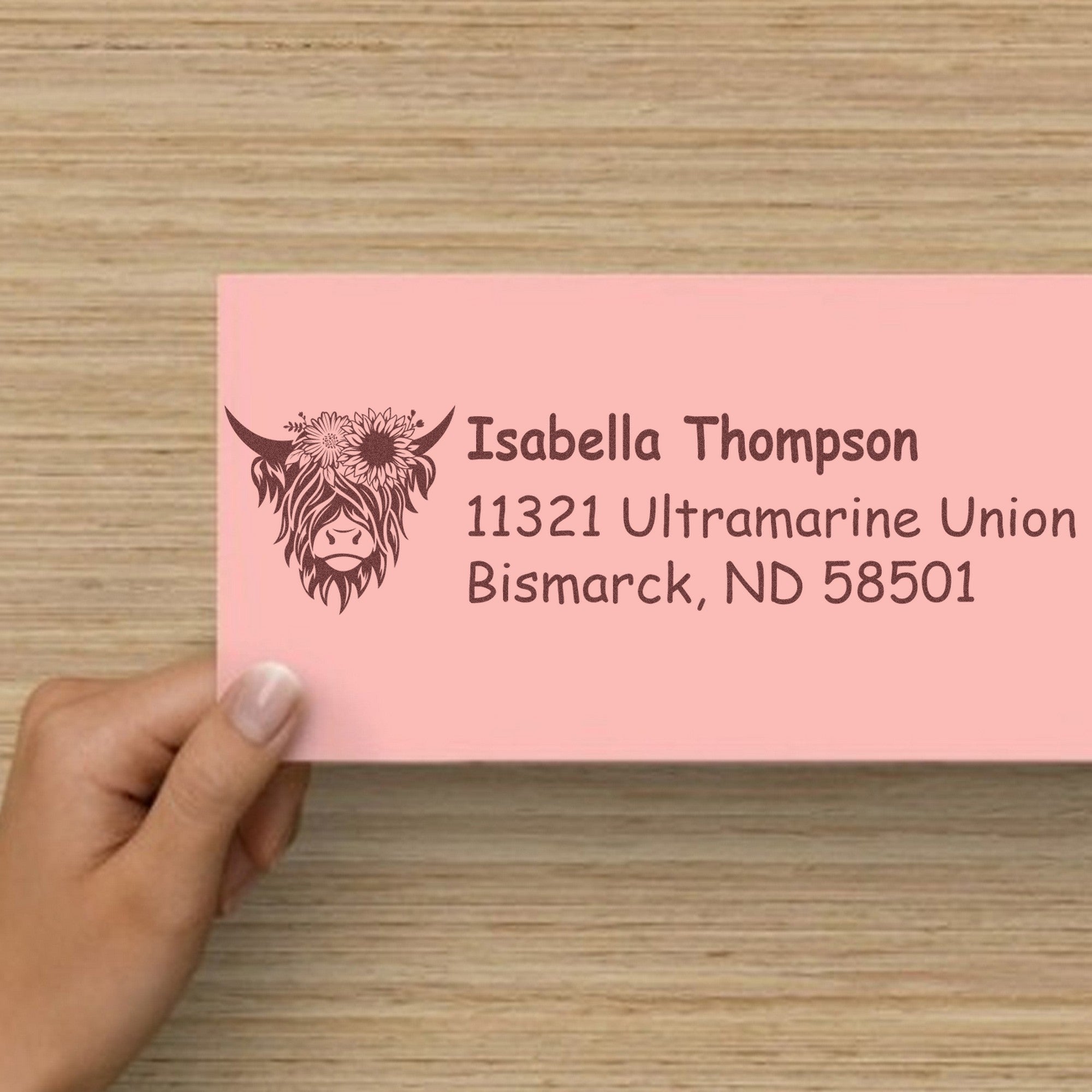 Pink custom address stamp and seal with floral Highland cow logo and brown text for Isabella Thompson, Bismarck ND