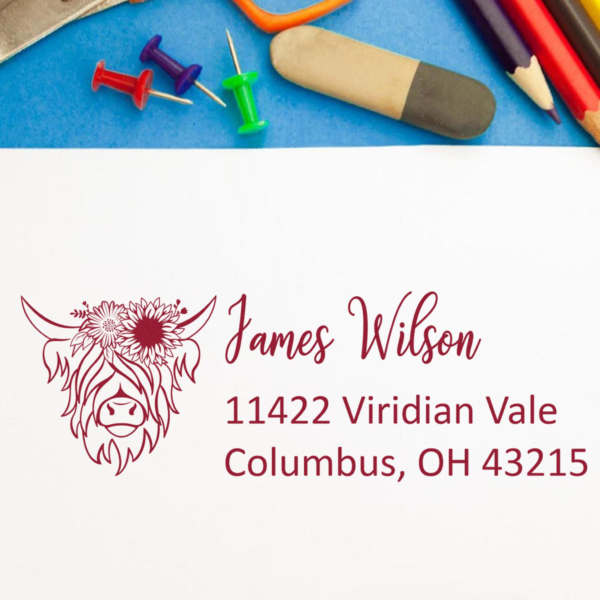 Maroon custom stamp and seal with buffalo graphic, James Wilson address, beside colorful stamping tools on blue.
