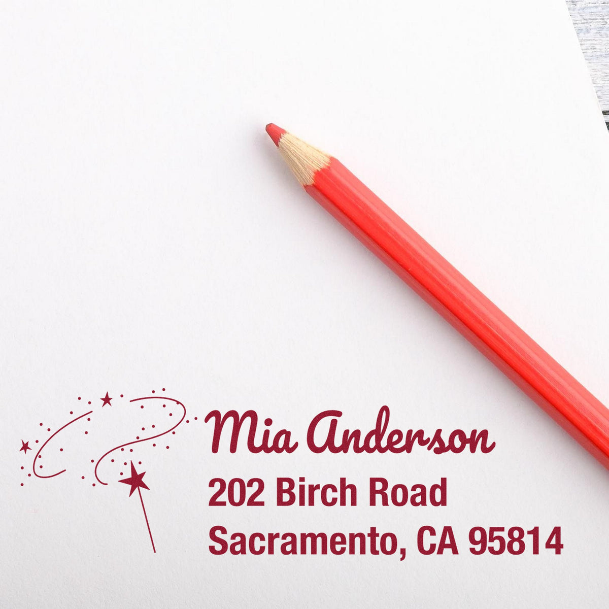 Red pencil on white paper with burgundy custom address stamp and seal reading Mia Anderson, 202 Birch Road, Sacramento, CA 95814.