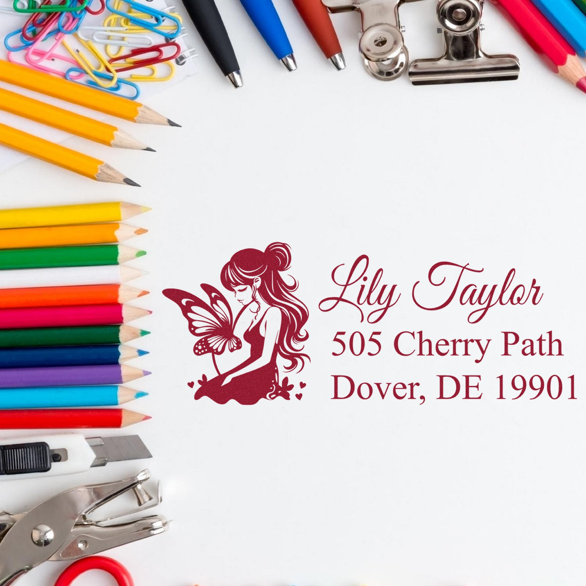 Personalized burgundy butterfly return address stamp with colored pencils, pens, clips, and seal tools.