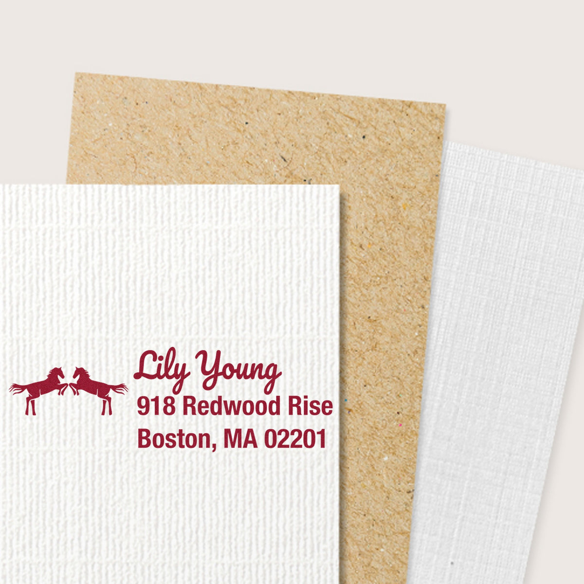 Custom burgundy address stamp and seal samples with horse logo on white textured paper, plus kraft and white swatches.