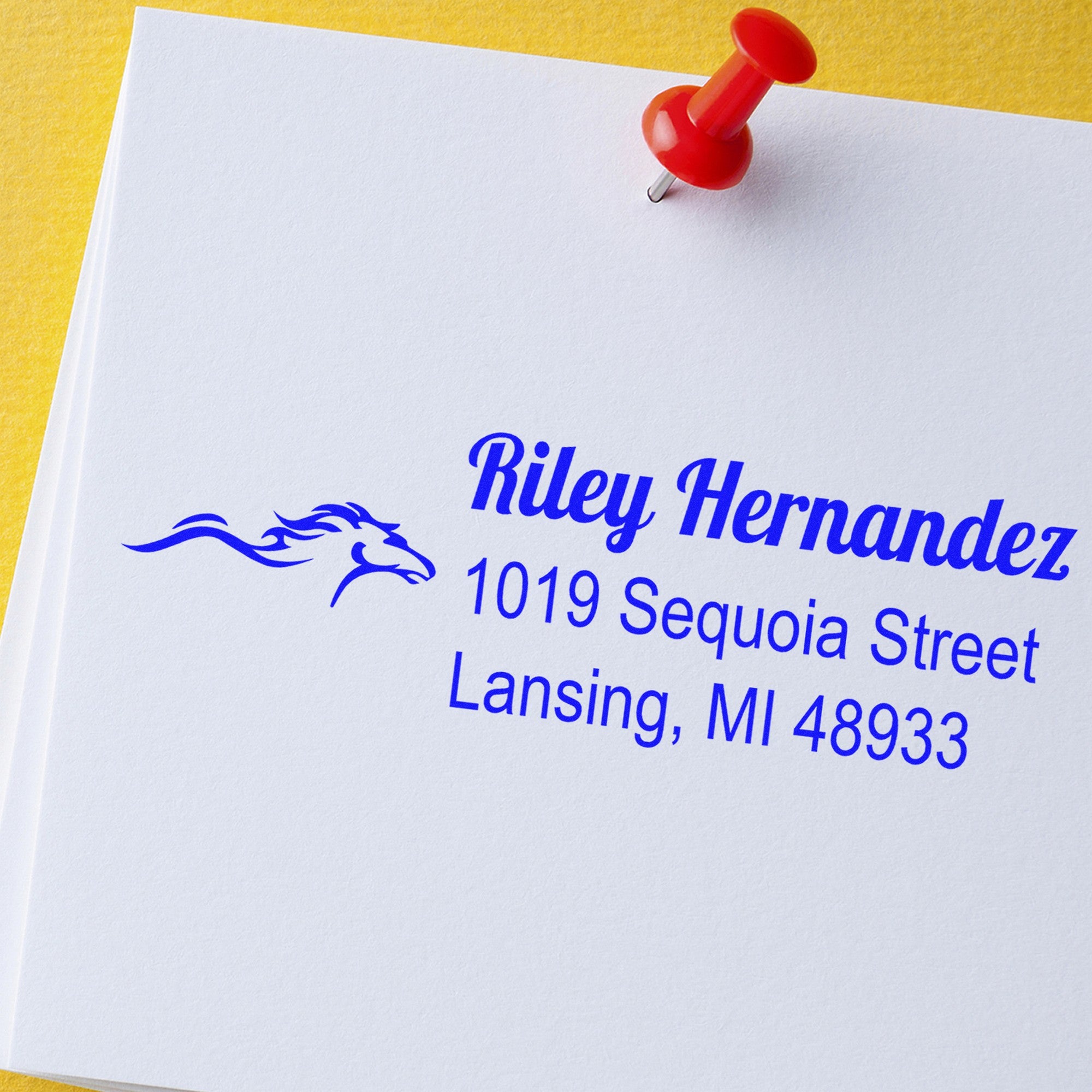 Red push pin seal on white paper with blue custom address stamp and logo on yellow background