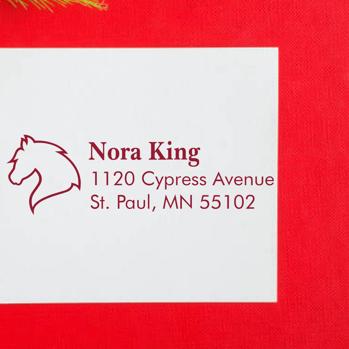 Custom maroon horse-head address stamp and seal on a white card, set against a bright red background.