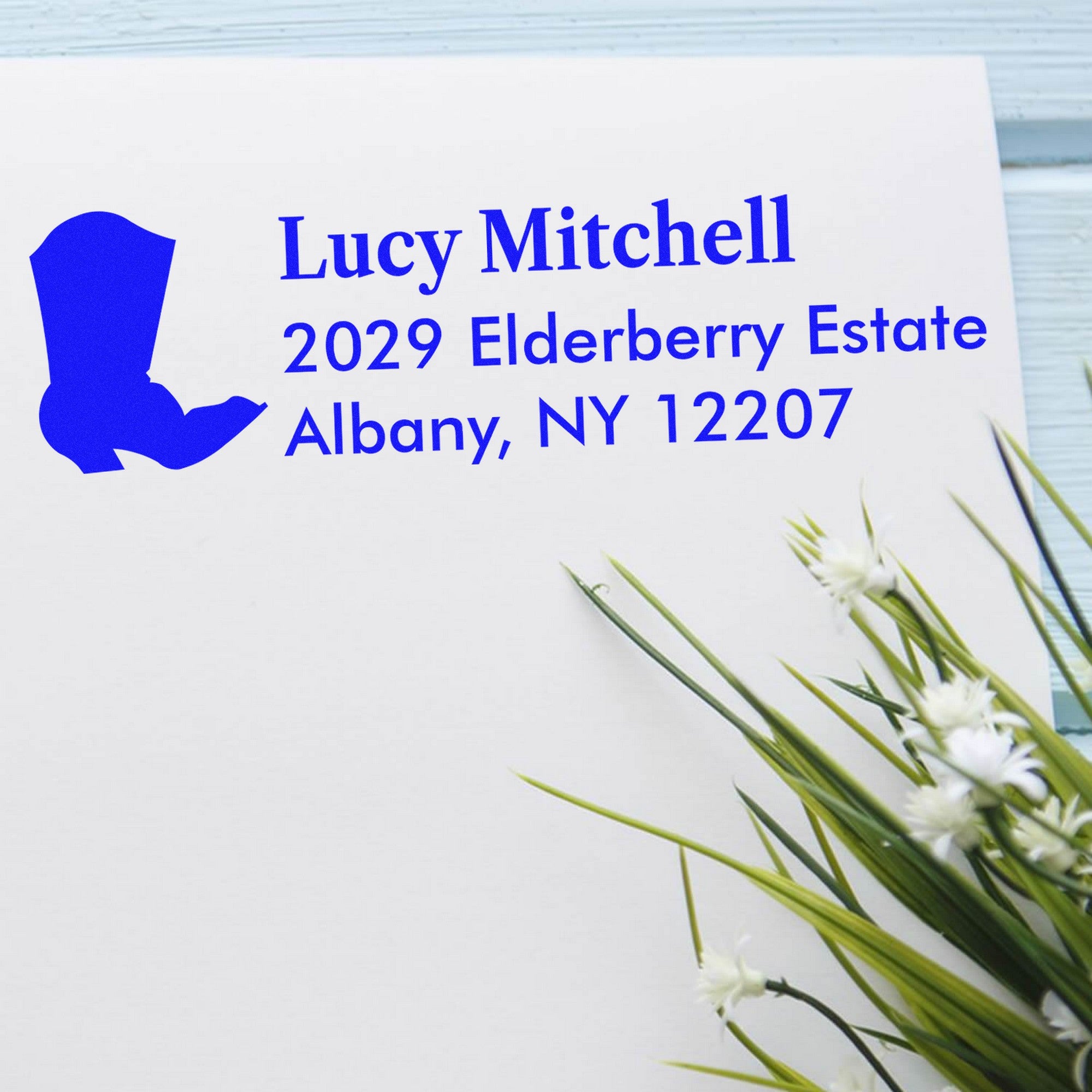 Blue custom stamp and seal for Lucy Mitchell, 2029 Elderberry Estate, Albany, NY 12207 on white card.