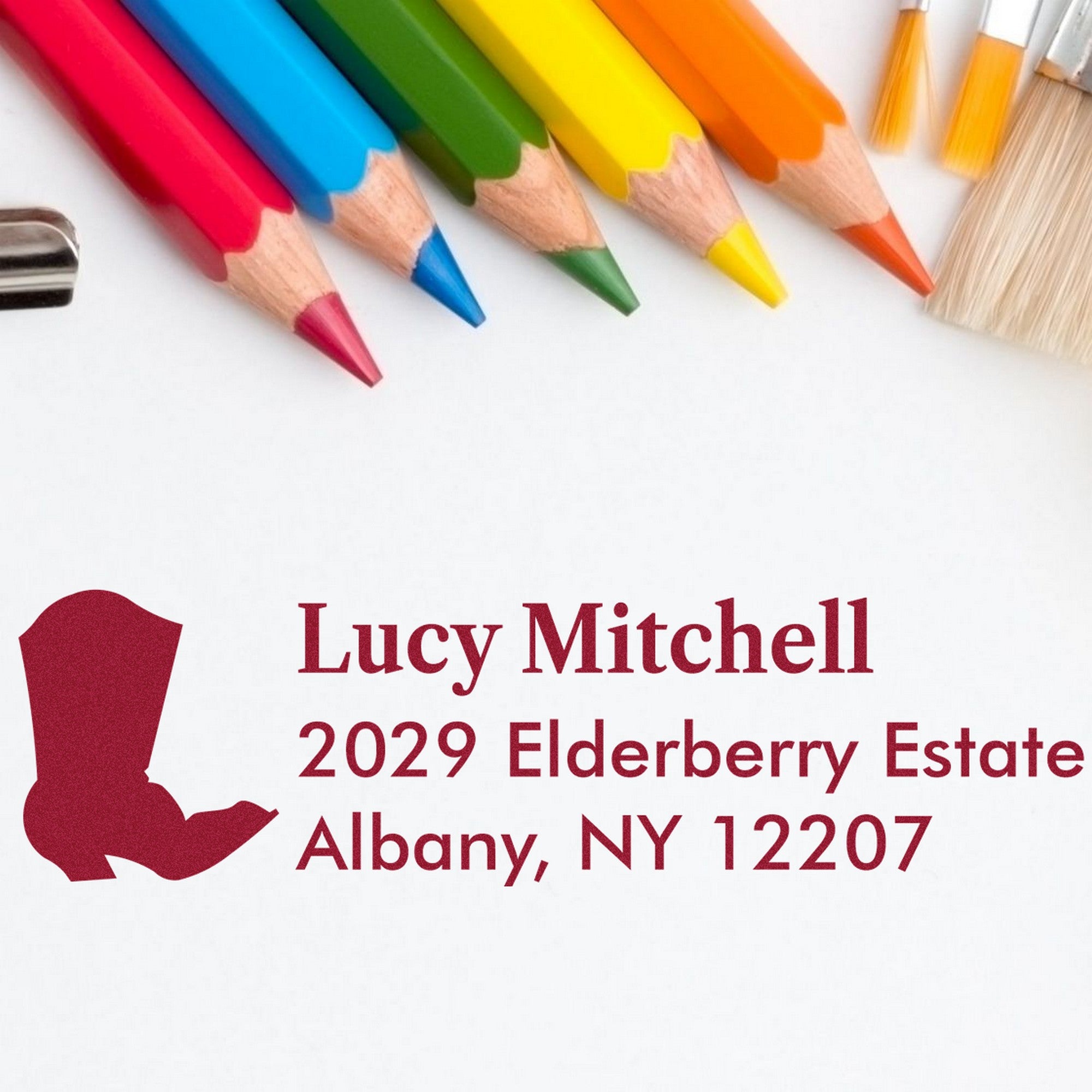 Colorful pencils beside a burgundy custom stamp and seal for Lucy Mitchell, 2029 Elderberry Estate, Albany, NY 12207.