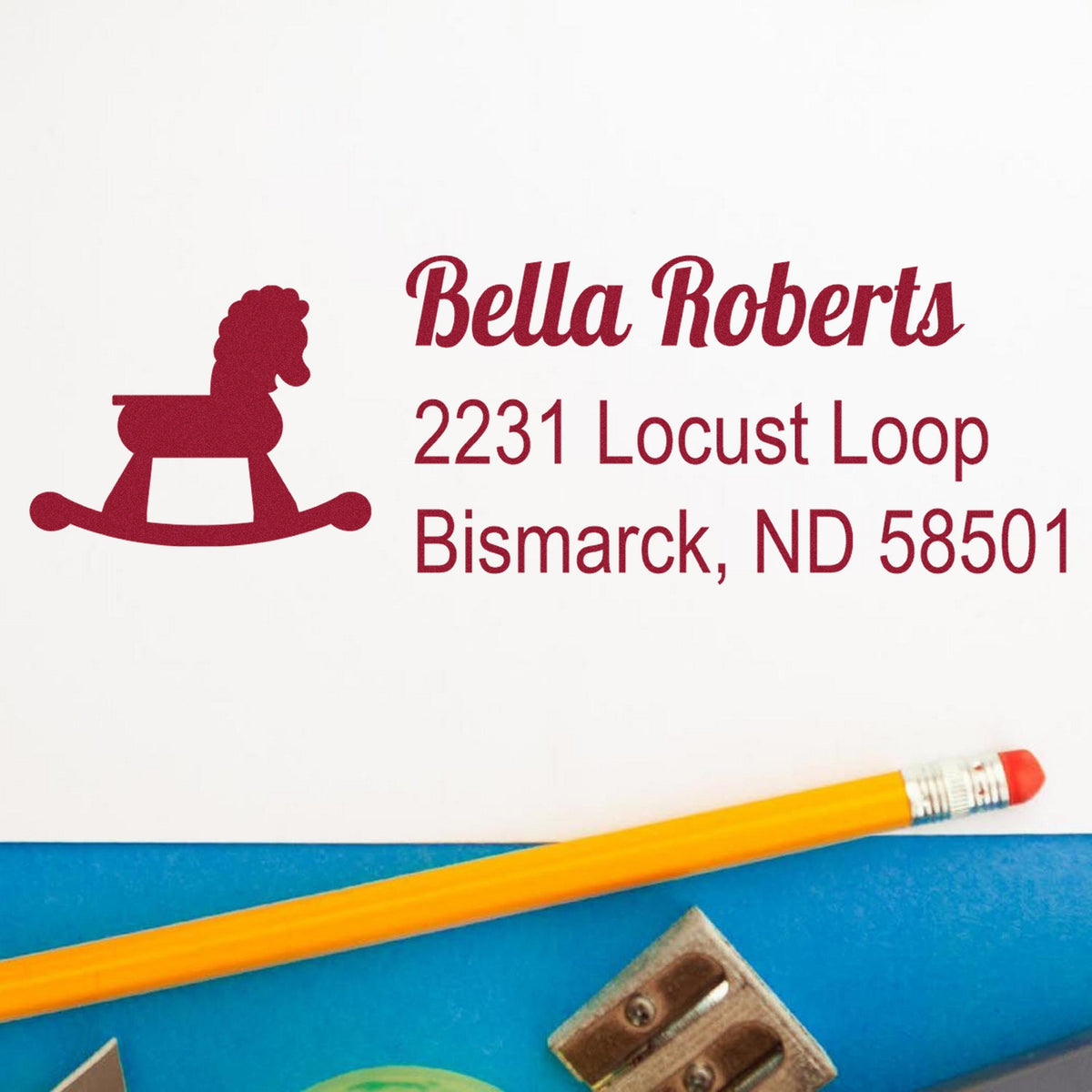 Custom maroon rocking horse return address stamp for Bella Roberts, 2231 Locust Loop, Bismarck, ND 58501, on white.