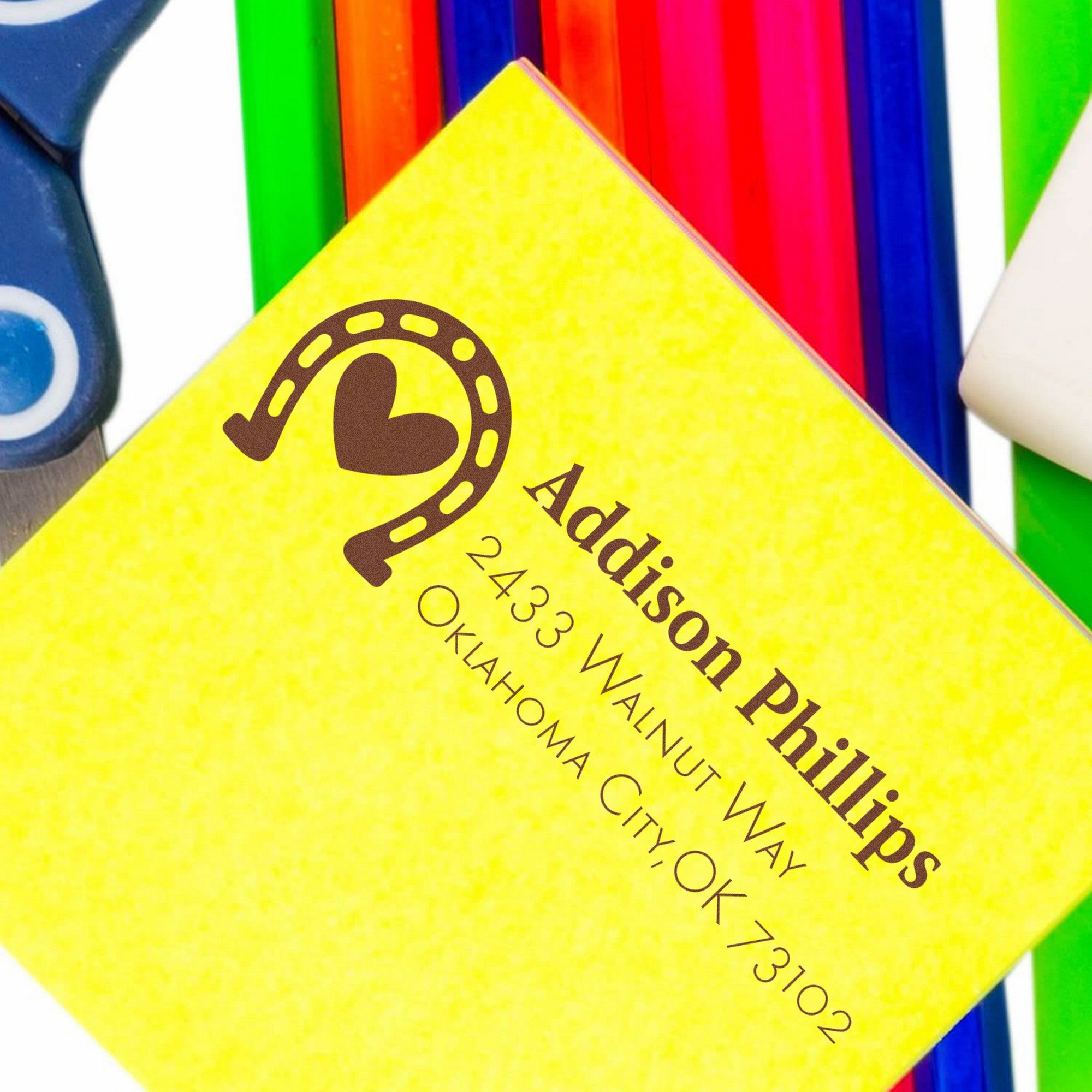 Yellow stamp and seal card with brown Addison Phillips logo, set against bright rainbow pens and markers.