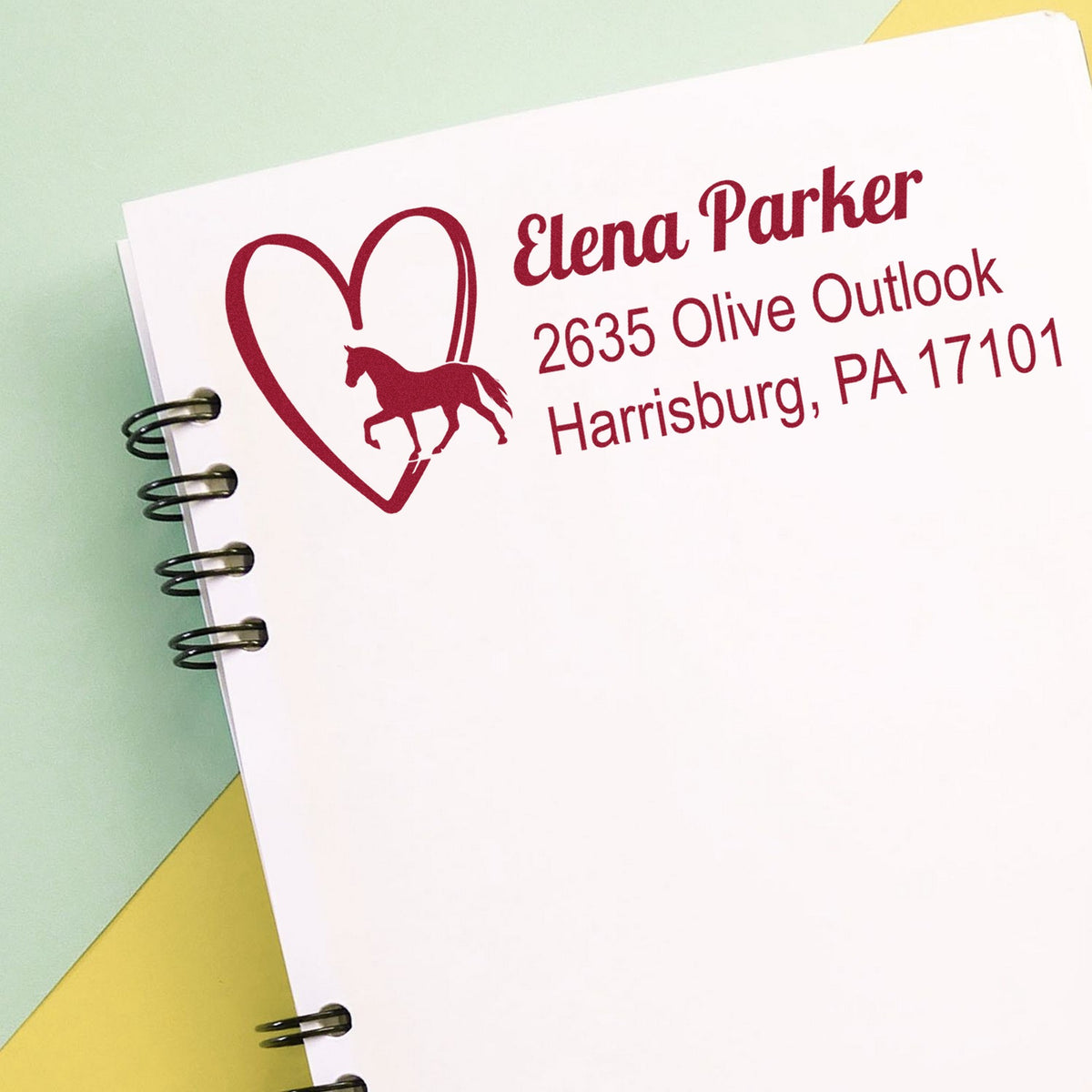 Burgundy horse heart seal stamp on white card with Elena Parker address, spiral-bound sample, pastel green and yellow background.