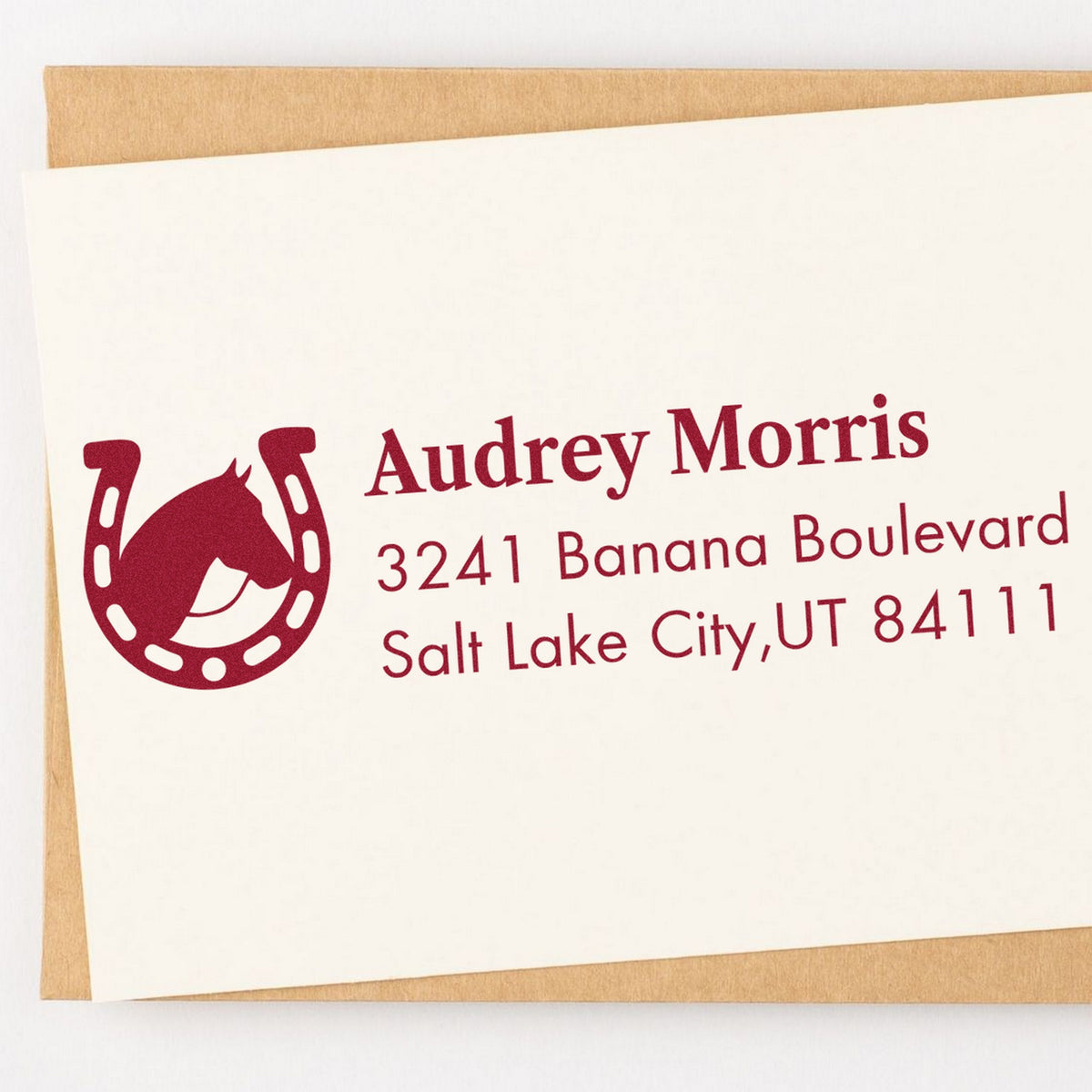 Burgundy self-inking return address stamp with horseshoe seal logo on cream envelope, Audrey Morris, Salt Lake City, UT.