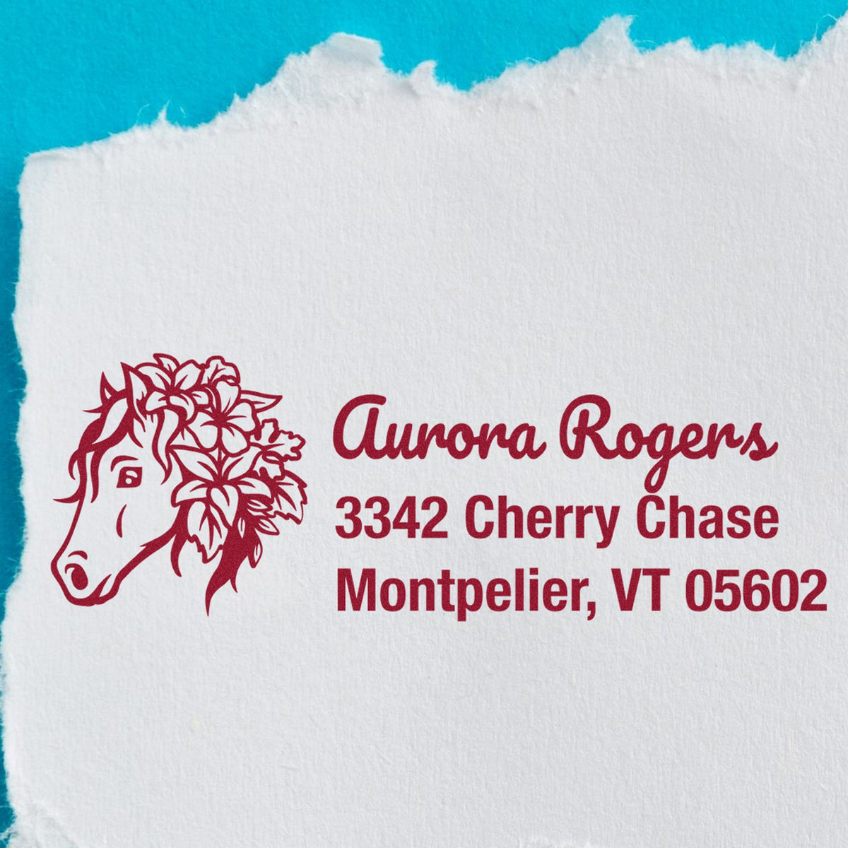 Maroon custom address stamp and horse seal on white paper, reading Aurora Rogers, 3342 Cherry Chase, Montpelier, VT 05602