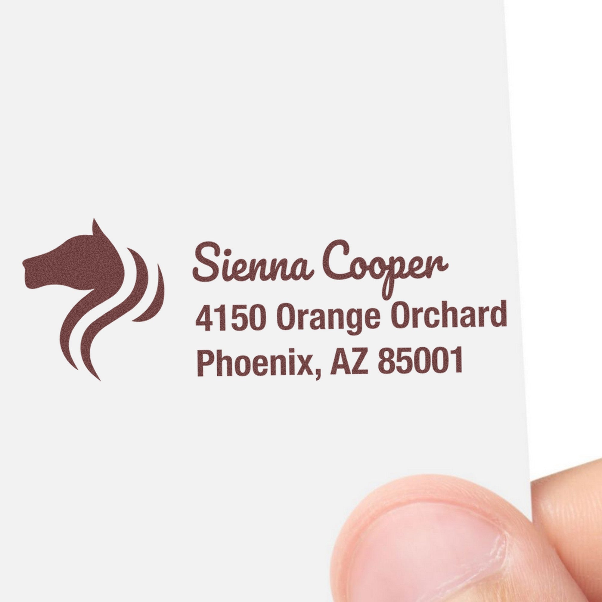 Maroon custom rubber address stamp with horse logo and Sienna Cooper, 4150 Orange Orchard, Phoenix, AZ 85001 on white card.