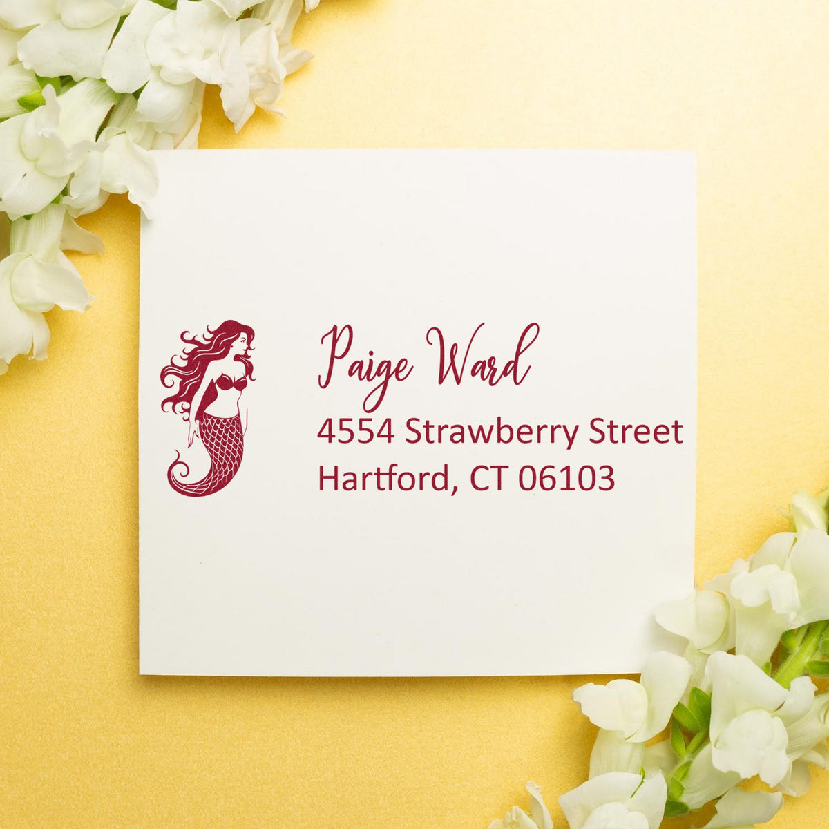 Burgundy mermaid address stamp and seal on white card, set against a gold background with white flowers.