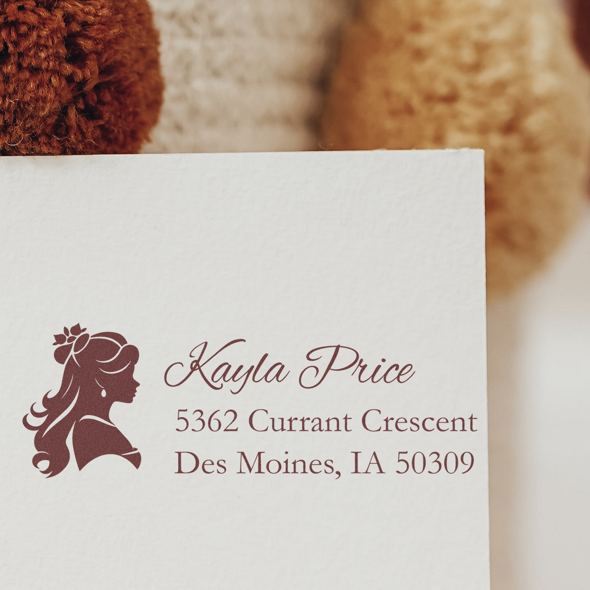Maroon custom stamp and seal design with female profile, Kayla Price name, and address on white paper