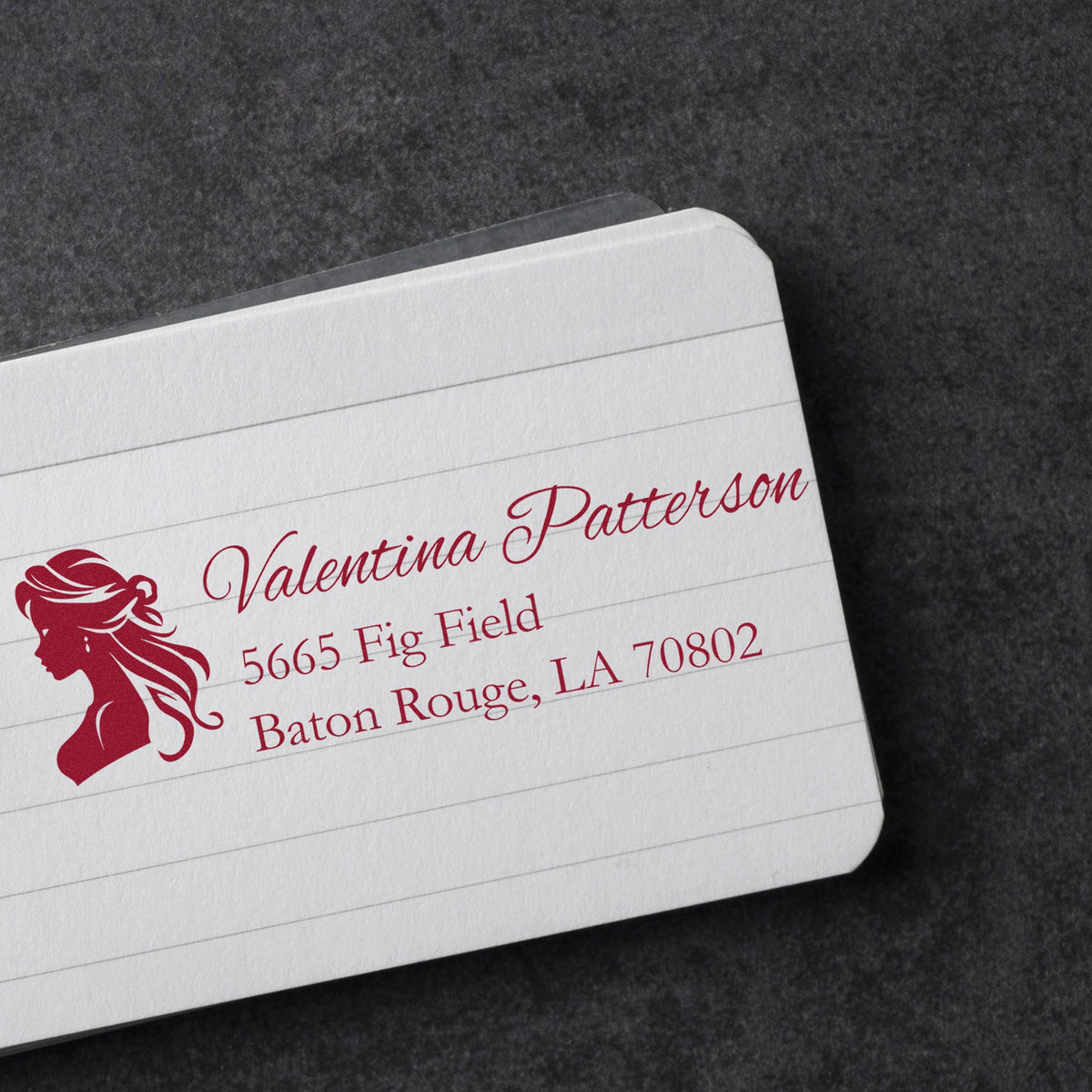 Custom red address stamp and seal-style logo on white lined paper against a dark textured background.
