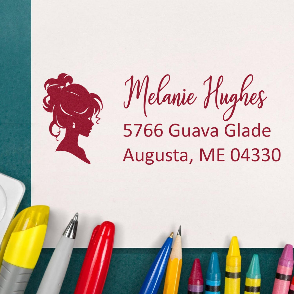Custom red stamp and seal with woman silhouette, Melanie Hughes, Augusta, ME 04330, on white paper with colorful pens.