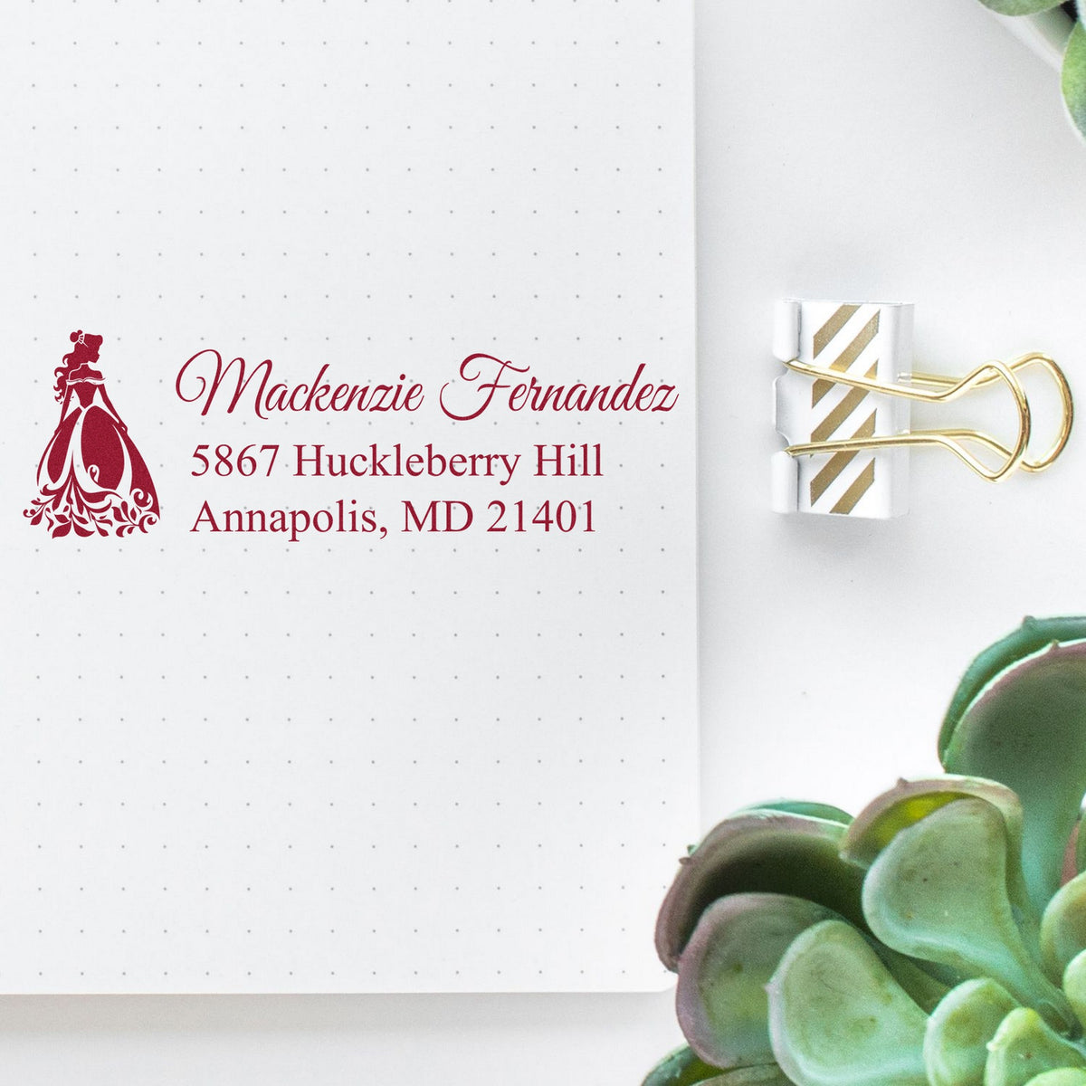 Burgundy custom address stamp with elegant script and clear gold-striped seal clipped on white dotted paper