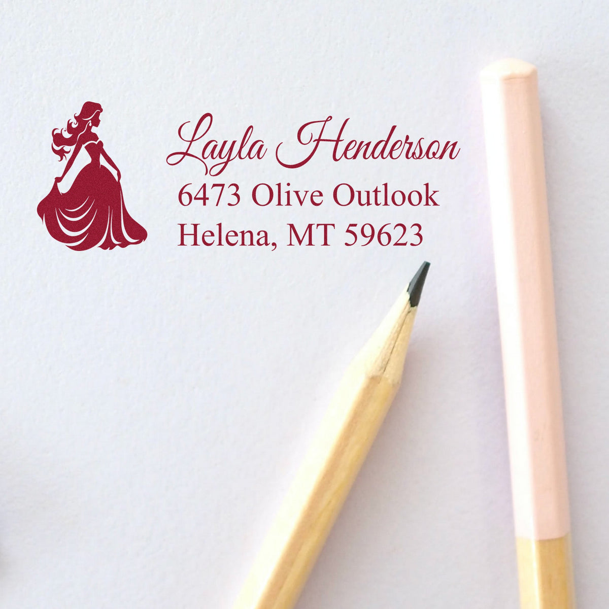 Burgundy custom stamp and seal with elegant woman silhouette, script name, and address on white paper.