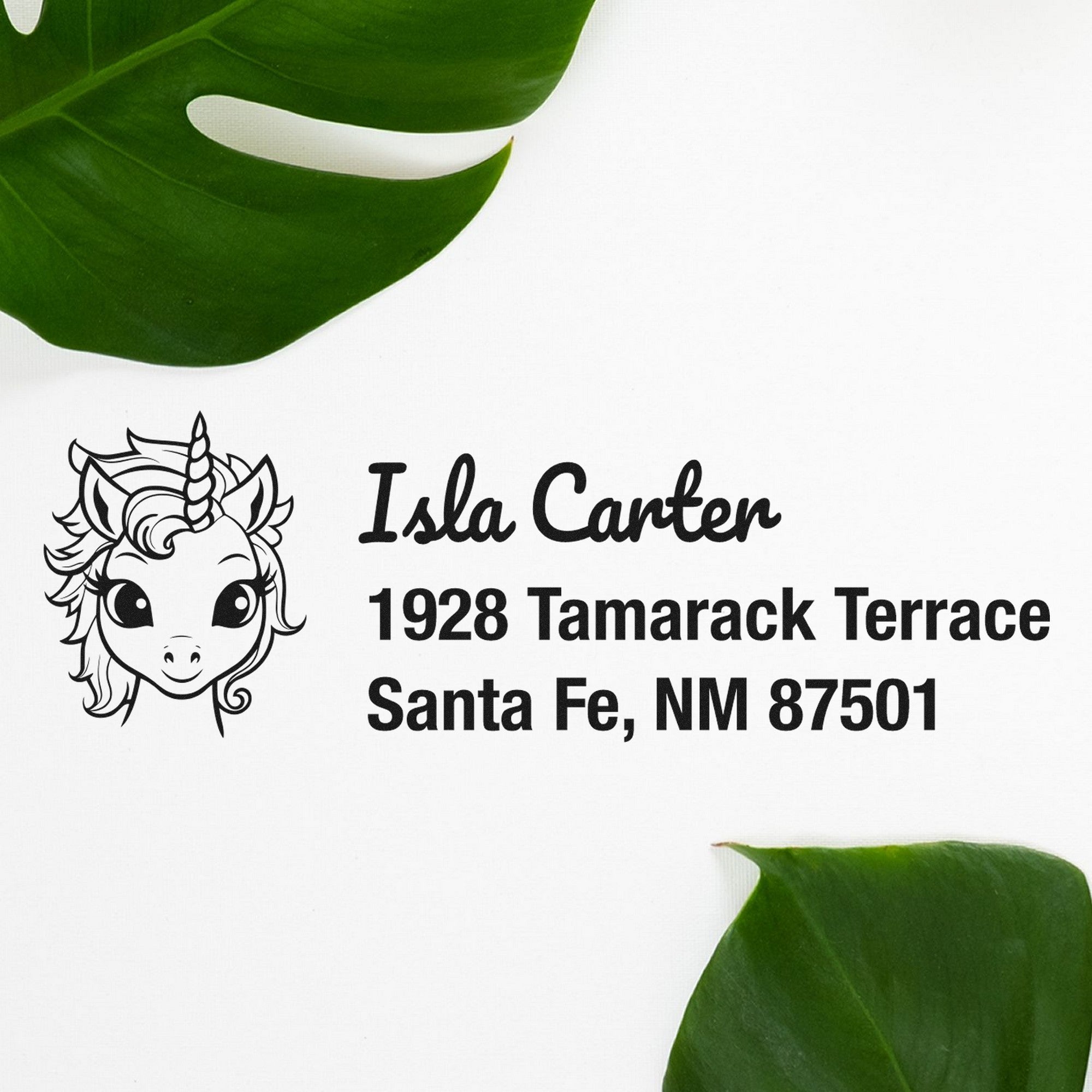 Custom self-inking stamp and seal with unicorn logo, black address text on white, framed by green leaves.