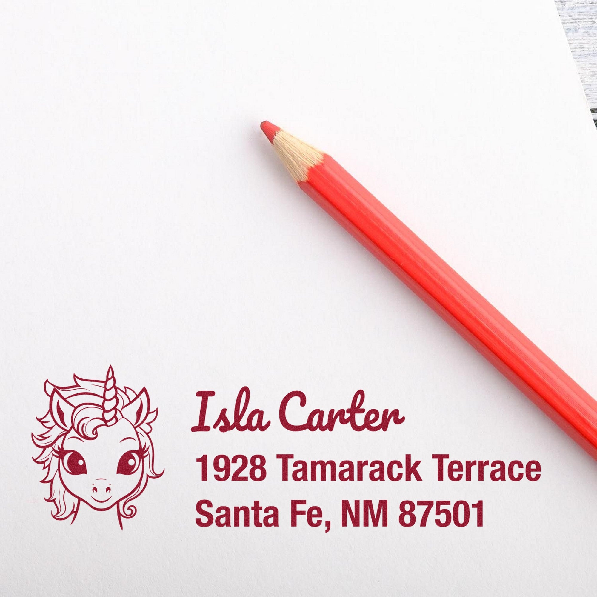 Red pencil on white paper with burgundy unicorn custom address stamp and seal for Isla Carter, Santa Fe, NM 87501