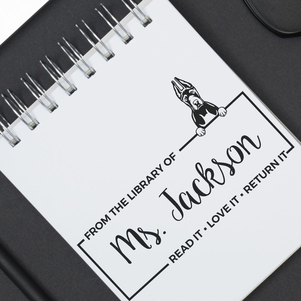 Black-and-white custom library stamp and seal with dog graphic, From the library of Ms. Jackson and Read it, love it, return it.
