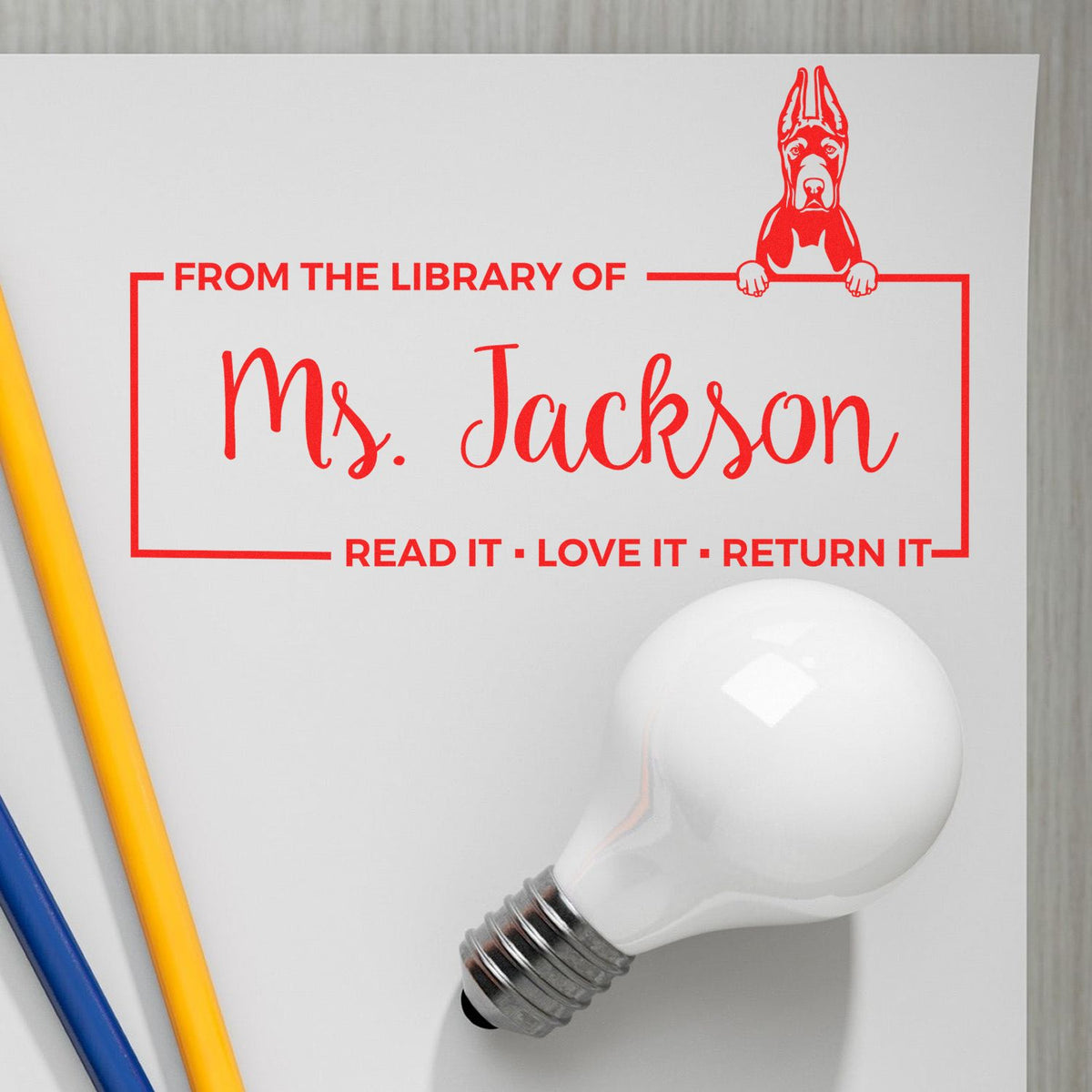 Red dog library stamp seal reading From the Library of Ms. JacksonRead it, Love it, Return it on white paper.