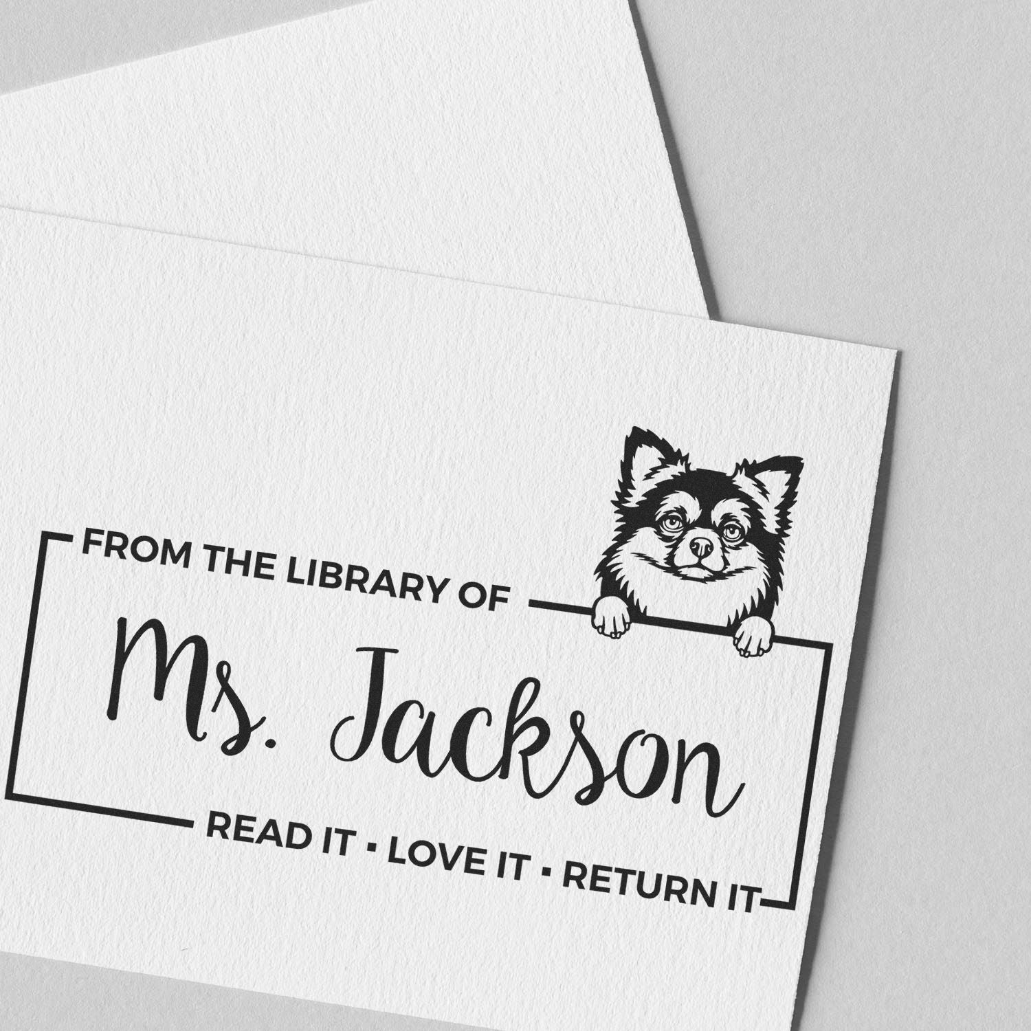 Black custom library return stamp and seal with a dog illustration, Ms. Jackson text, on white paper.