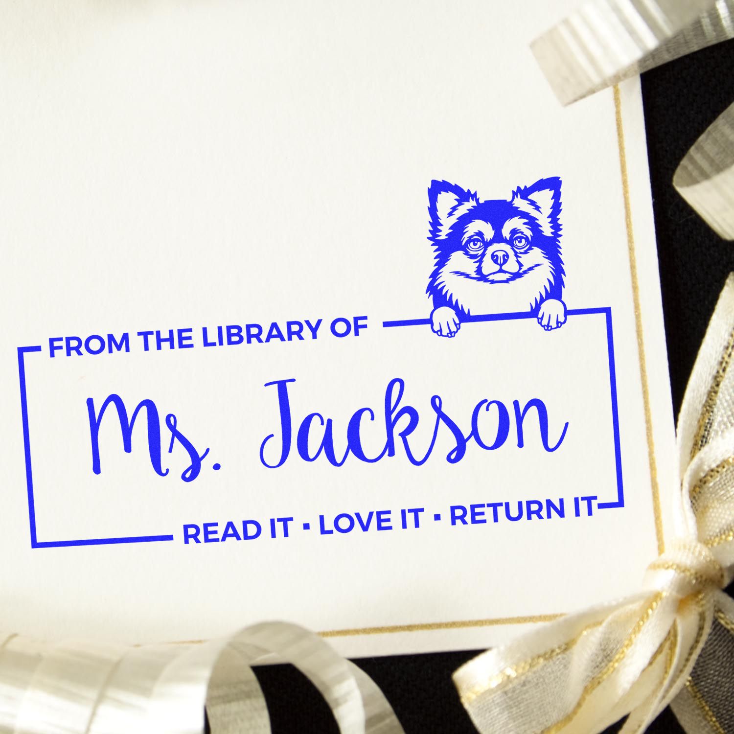 Blue custom library stamp and seal reading ĀFrom the Library of Ms. JacksonĀ with dog mascot on white card