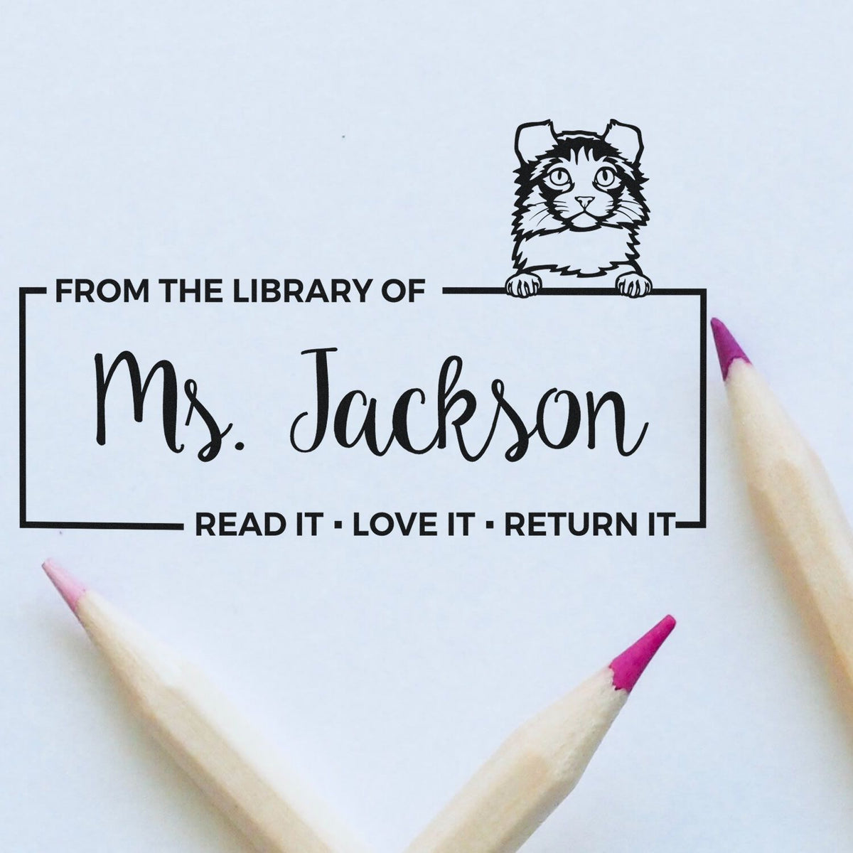 Black custom library stamp seal for Ms. Jackson with cat mascot and pink-tipped pencils on white paper.