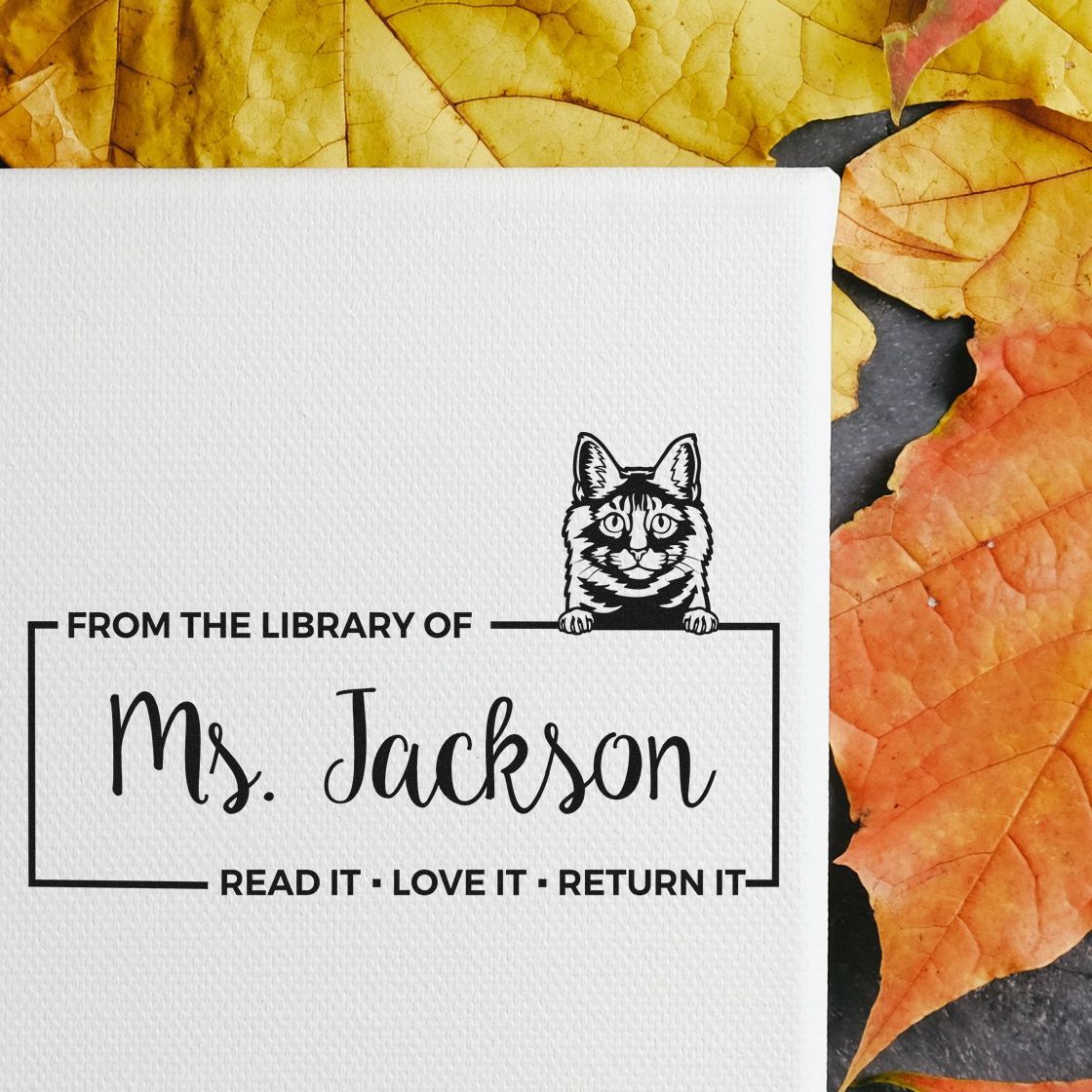 Custom black library stamp seal for Ms. Jackson with cat illustration on white card, surrounded by yellow and orange leaves.