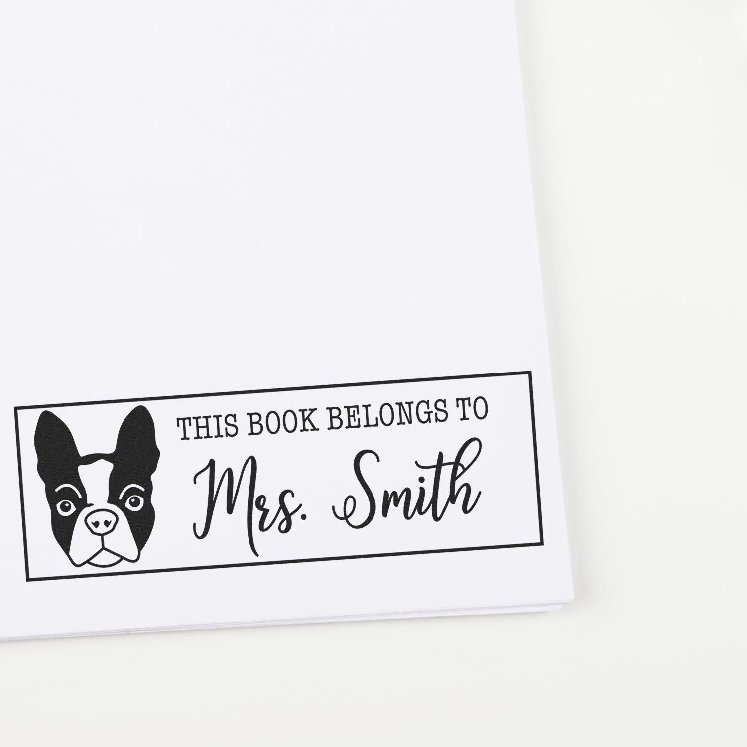 Black-and-white custom book stamp with Boston terrier illustration and This Book Belongs to Mrs. Smith text.