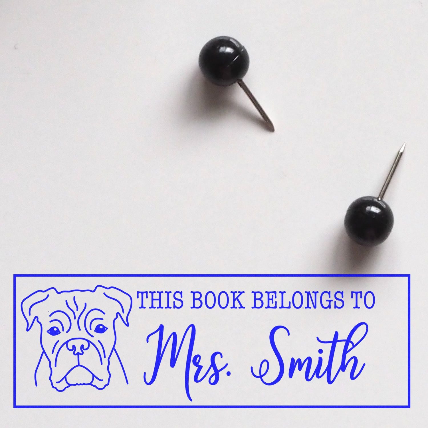 Wood handle Boxer dog rubber stamp with custom book identification text, in use on a white surface.
