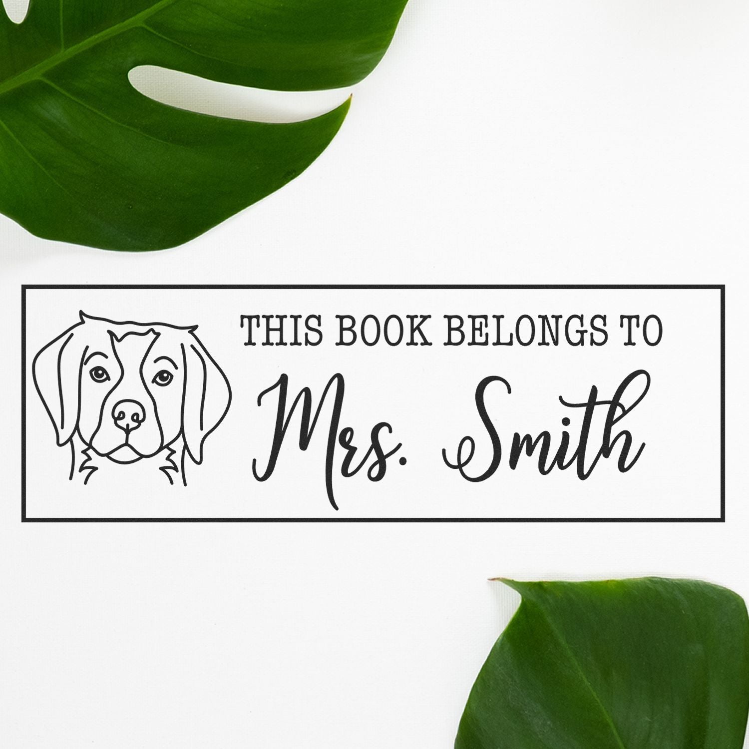 Personalized black book stamp and seal with dog illustration, This Book Belongs to Mrs. Smith, on white with green leaves.