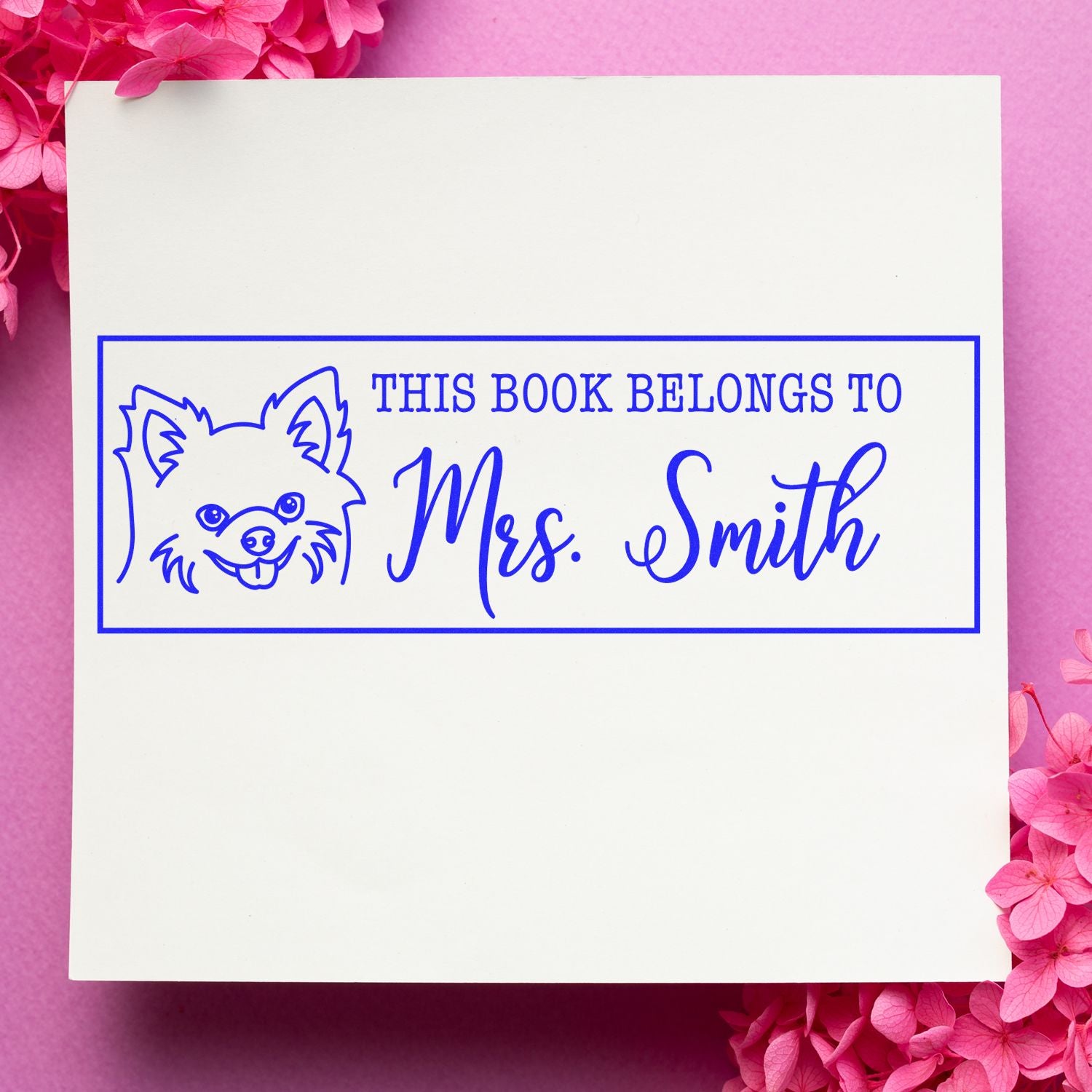 Blue custom book stamp and seal with dog outline, reading This book belongs to Mrs. Smith, on white with pink flowers.