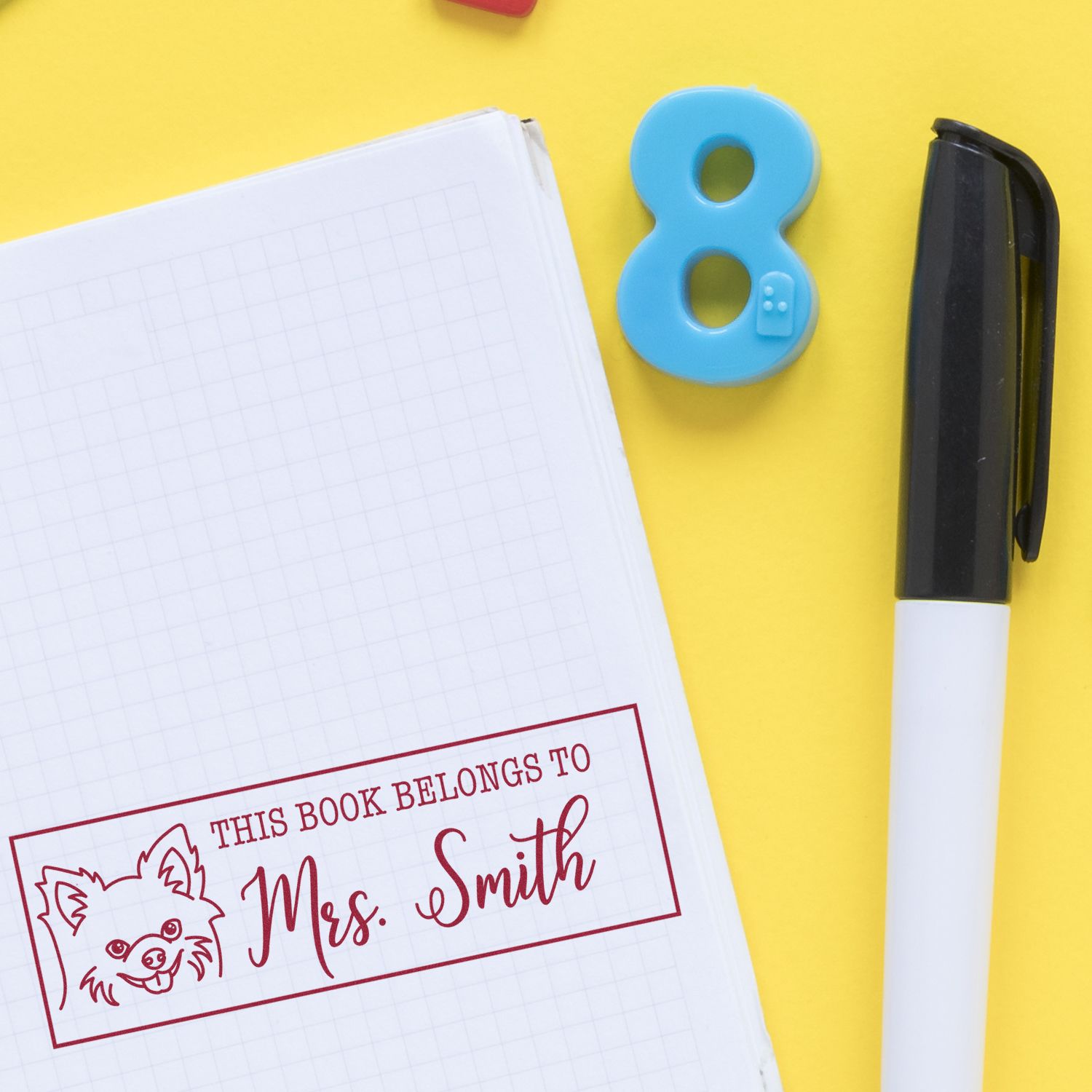Personalized red book stamp on notebook, blue number 8 seal, and black marker on bright yellow background.