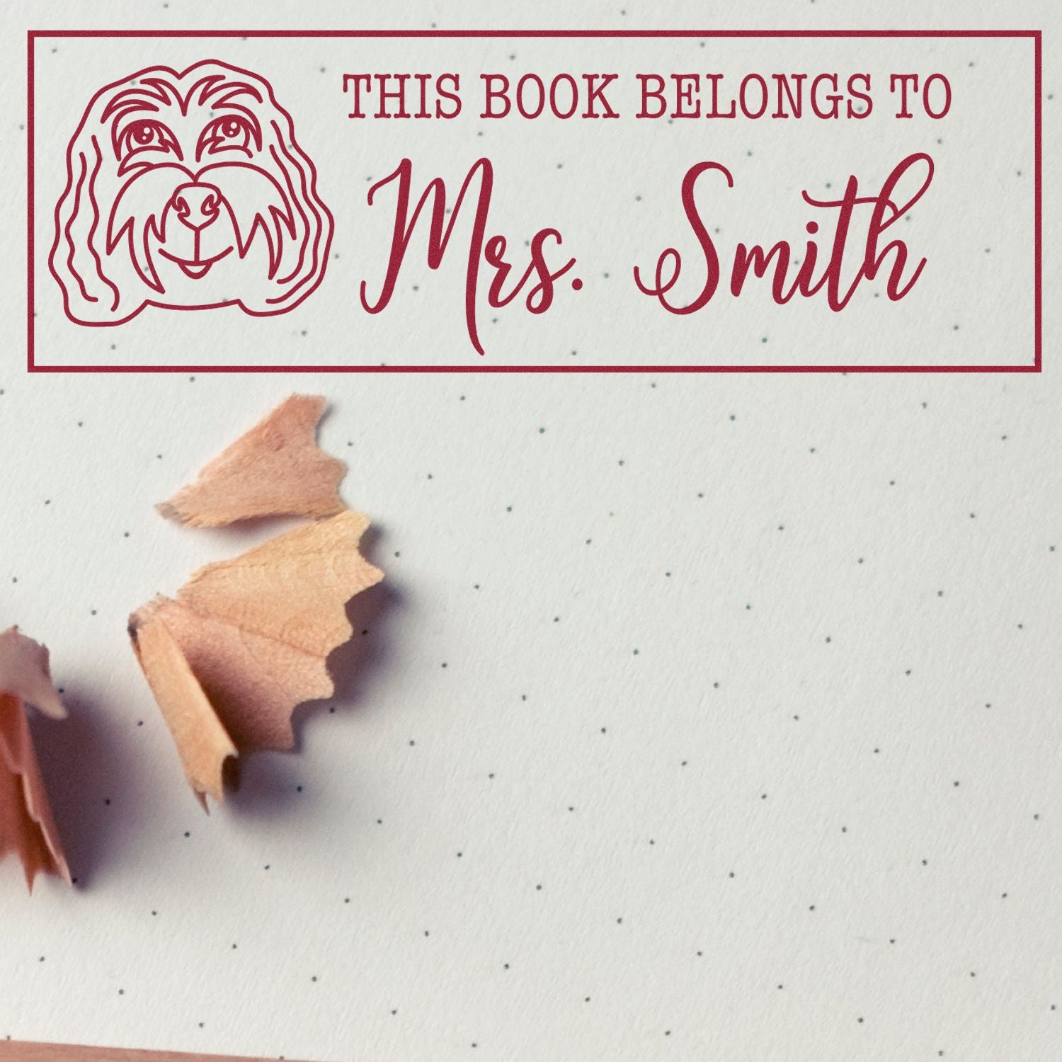 Red custom book stamp and seal with dog outline and This Book Belongs to Mrs. Smith on dotted paper.