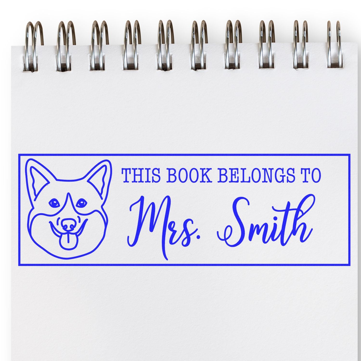 Blue custom book stamp seal with dog icon and This book belongs to Mrs. Smith on a white spiral notebook page.
