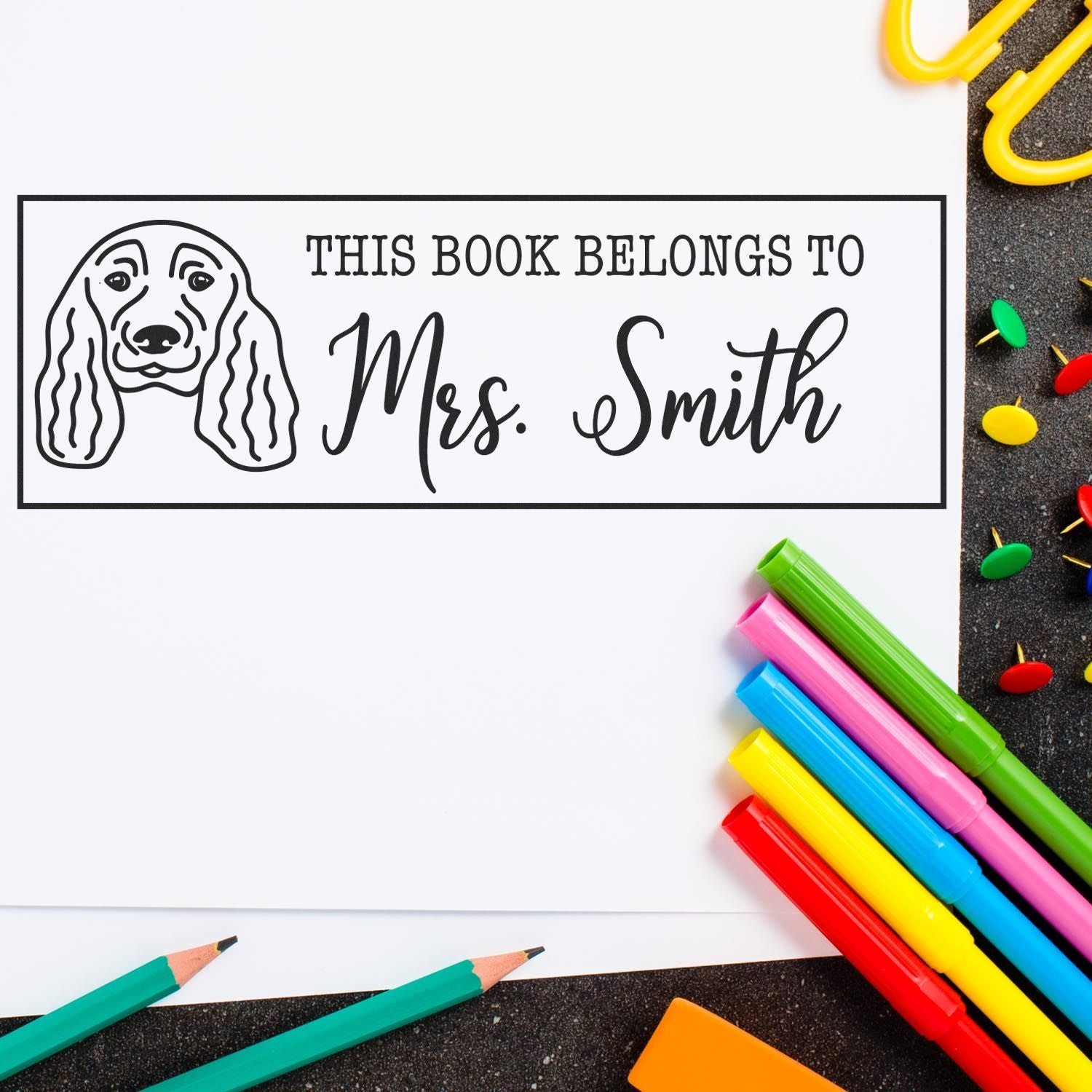 Personalized book stamp and seal with dog illustration, black lettering on white, reading This Book Belongs to Mrs. Smith.