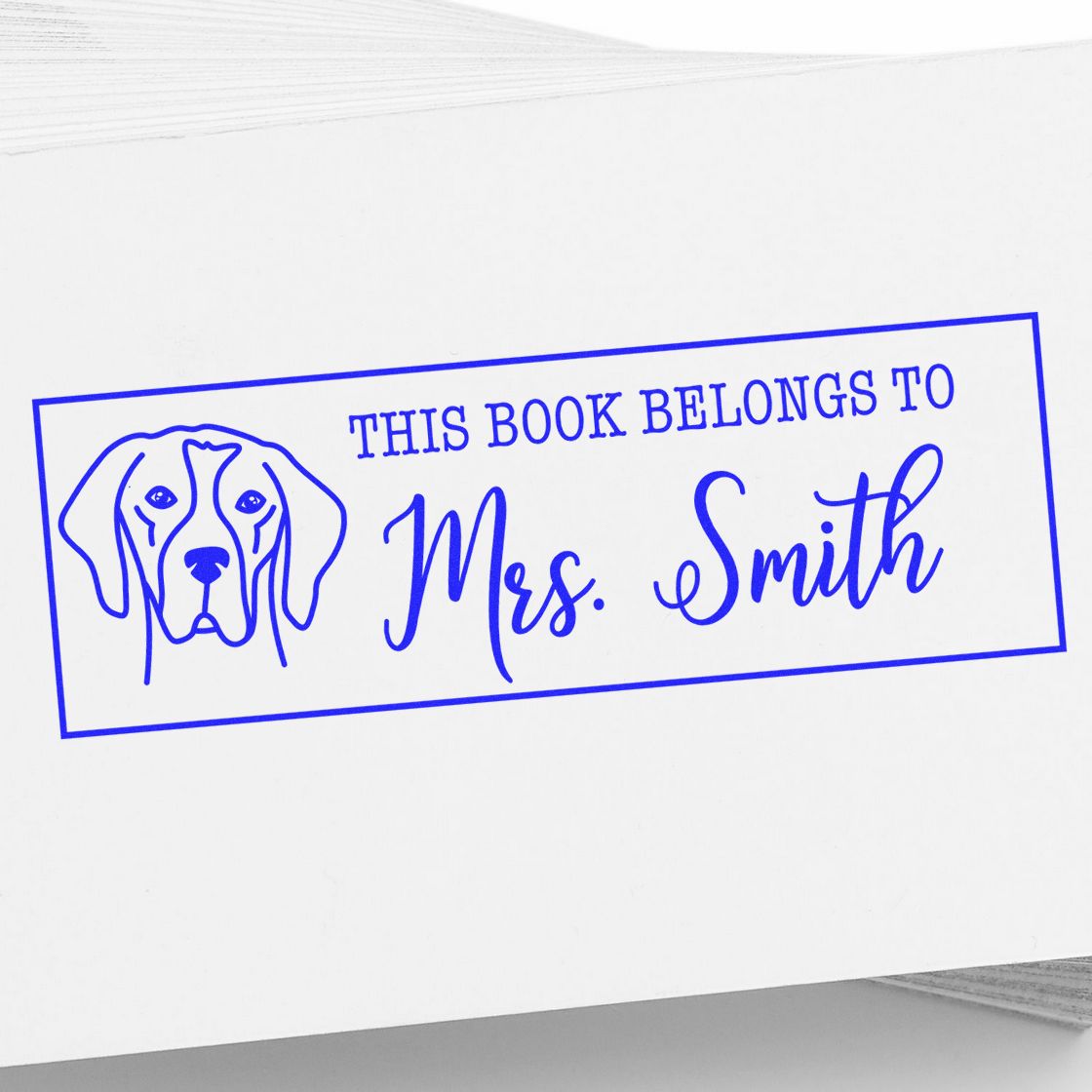 Blue custom book ownership stamp with dog illustration and This Book Belongs to Mrs. Smith in blue on white paper.