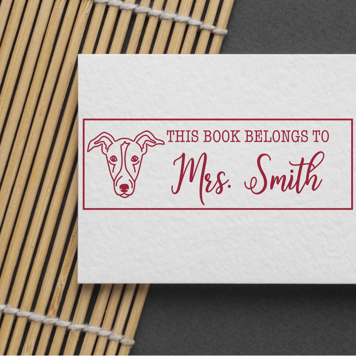 Greyhound dog stamp with a wooden handle from ESS, in use, featuring a customizable "belongs to" label.